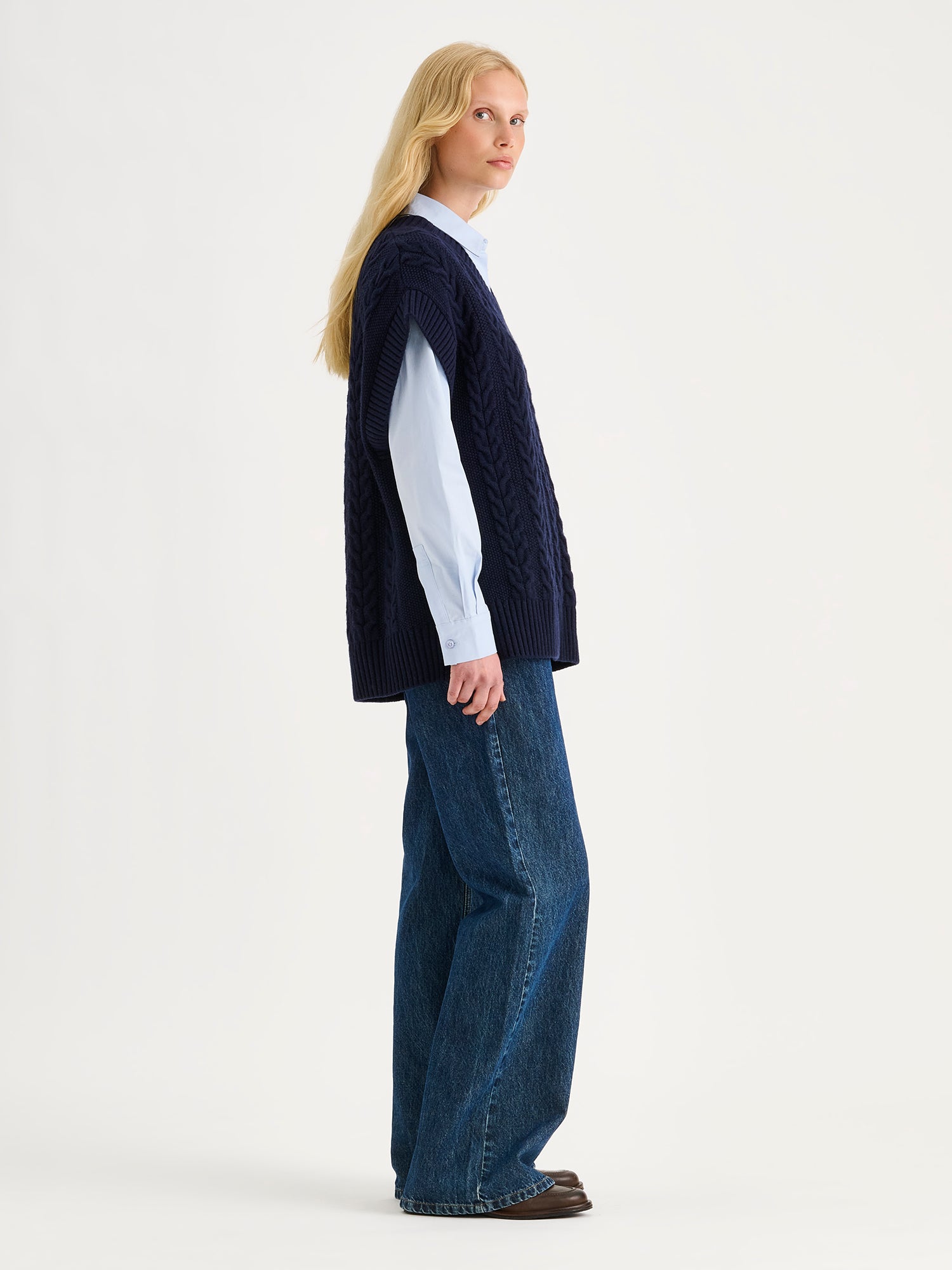 Nanso women's relaxed and generously cut Palmikot -knit vest on a blonde model with collared button up shirt and blue jeans
