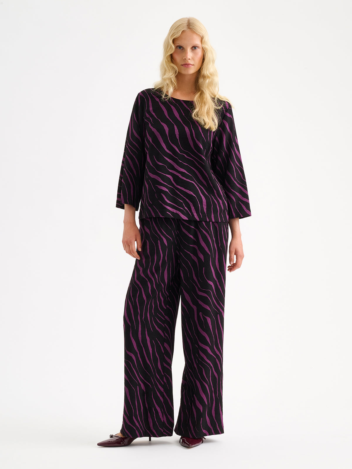 Nanso women's stylish Sypressi blouse showcases a striking print in black and violet, pictured on a model with matching trousers. | 36 - 174cm