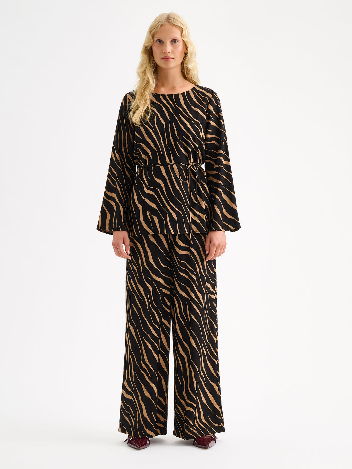 Nanso women's striking Sypressi trousers combine beautifully draping fabric with a trendy wide-leg silhouette. On a model with a matching blouse.