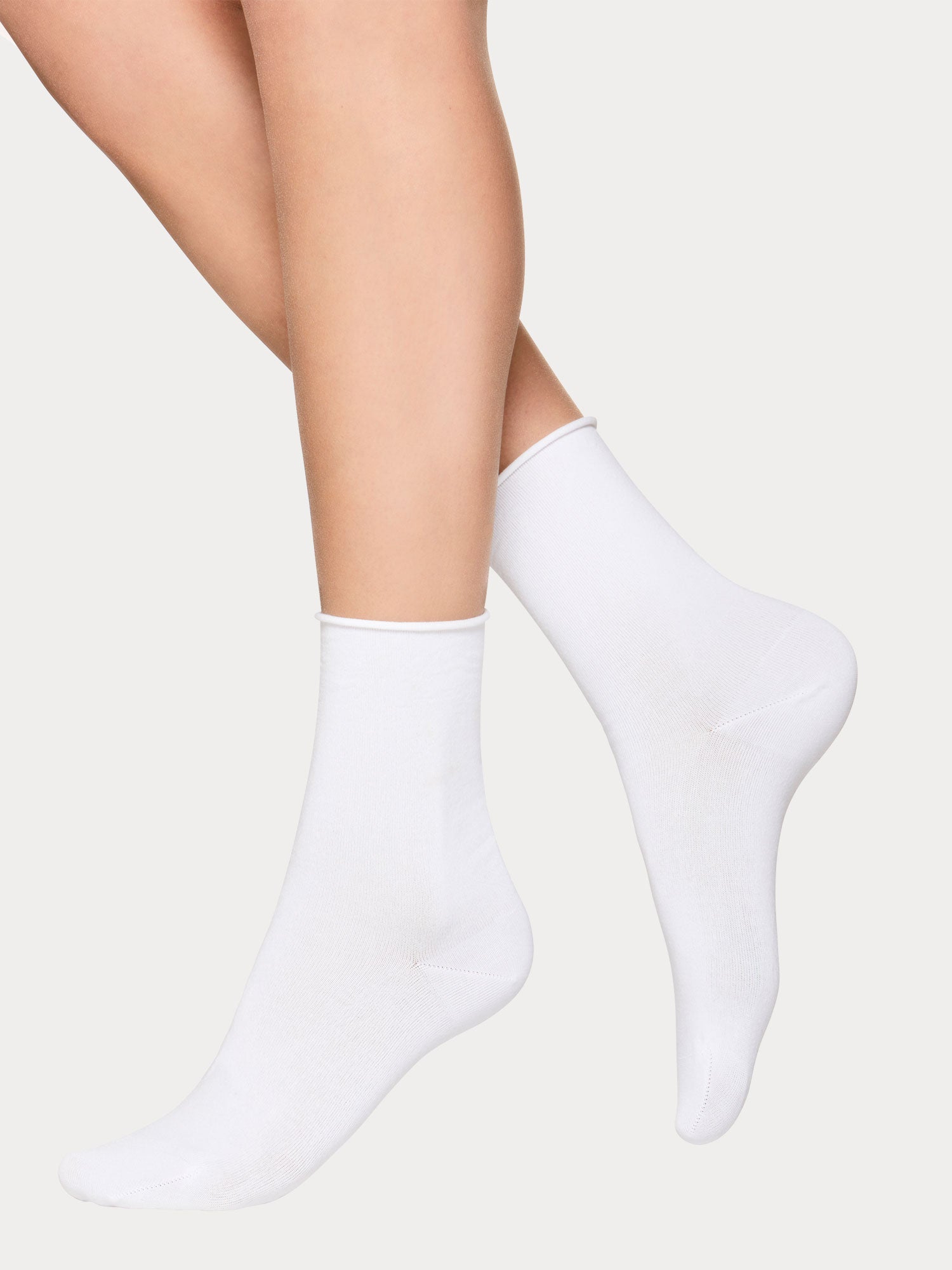 Vogue women's Cotton Comfort 2-pack of white and black cotton ankle socks. Crafted from premium cotton with a gentle rolled edge cuff. White pair on a model.