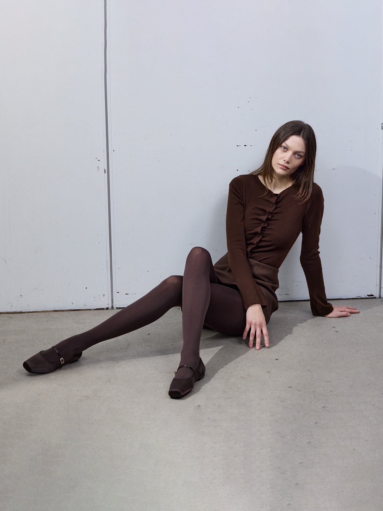 The model is placed in the middle of the photo with a full brown outfit with the Vogue Recycled Opaque tights.
