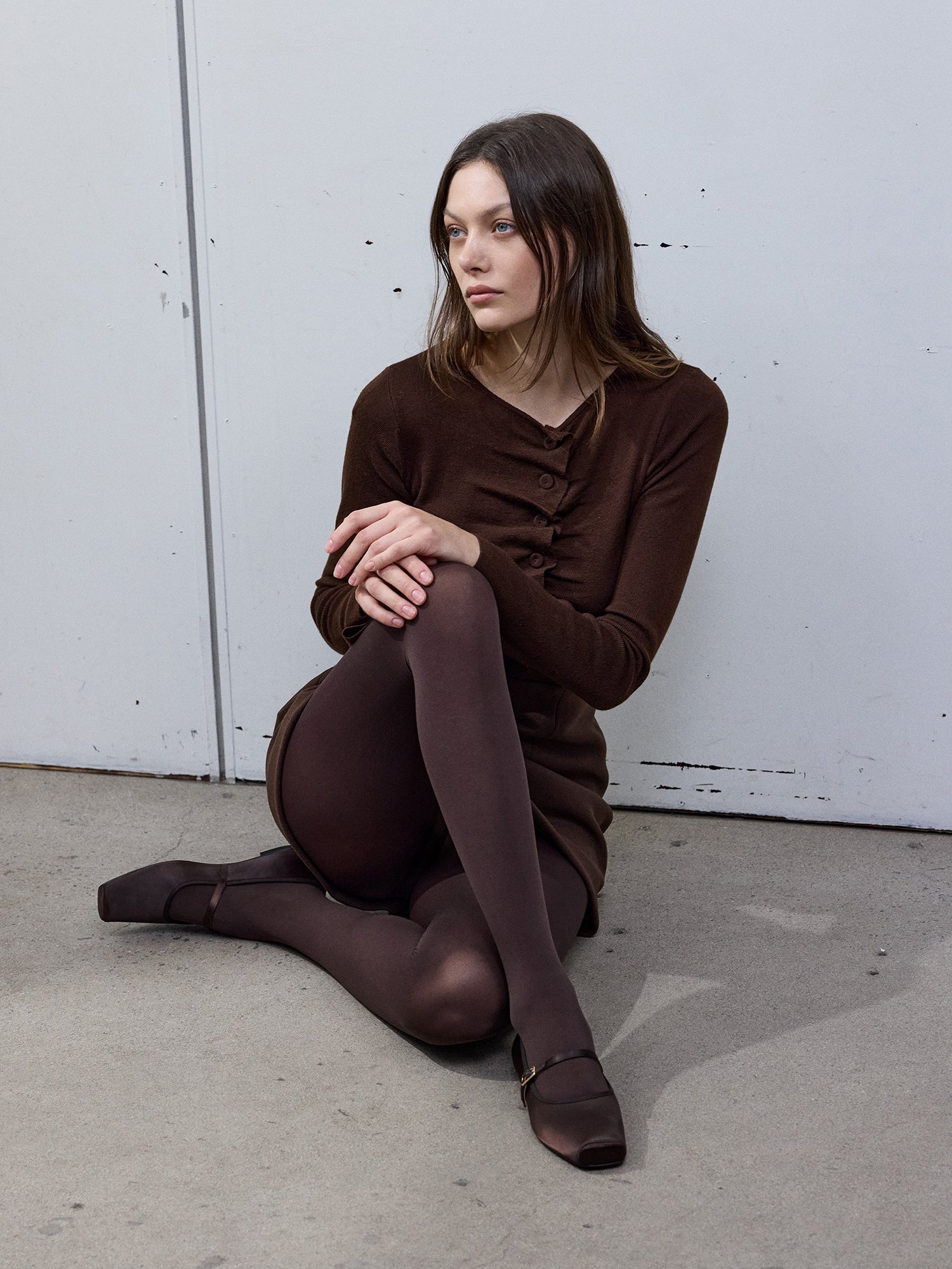 The model has full brown outfit with the matte cocoa brown tights. The picture is from the side of the model.