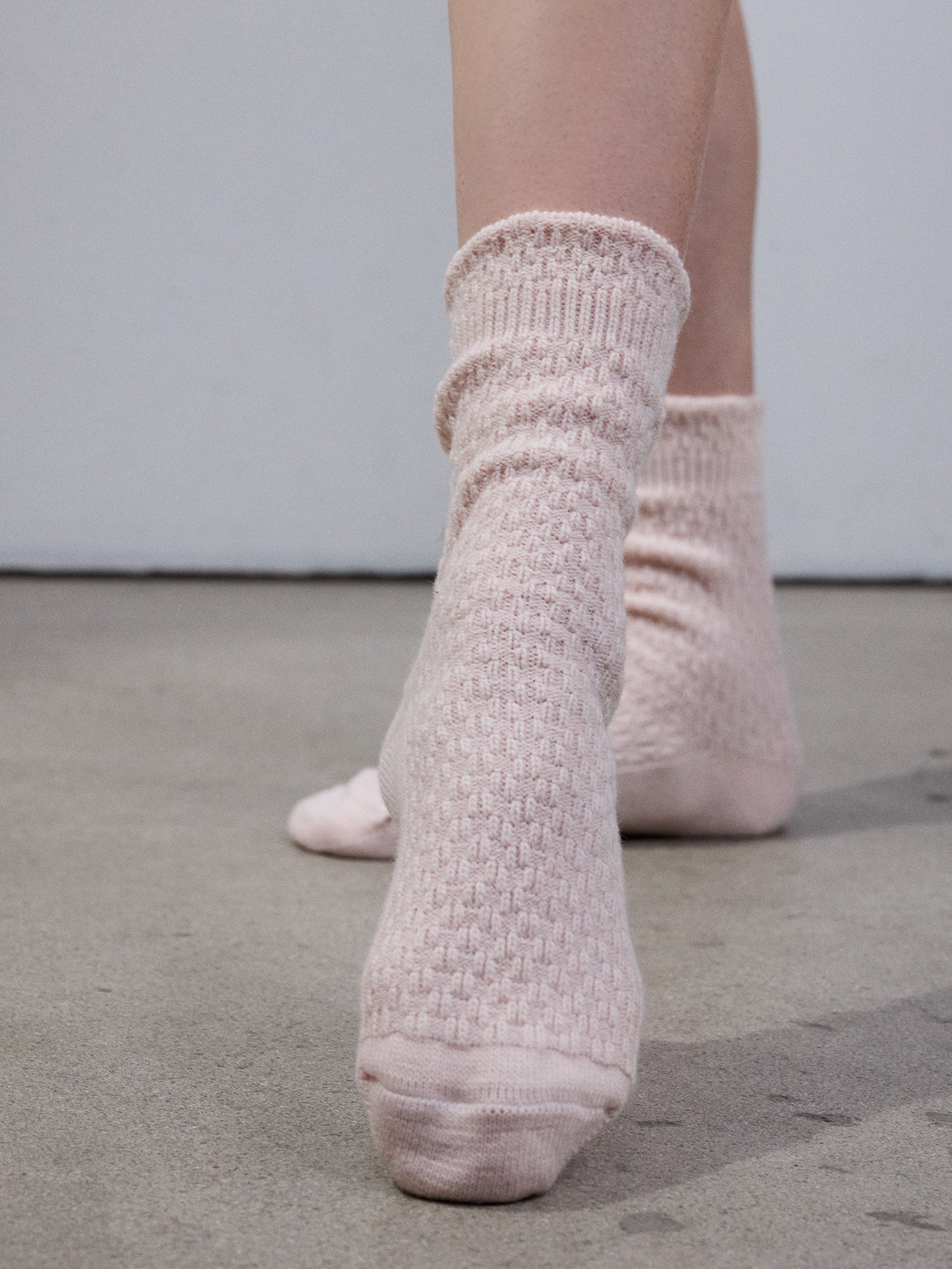 Vogue's Carina wool blend socks in powder rose with cable knit pattern in a product picture.