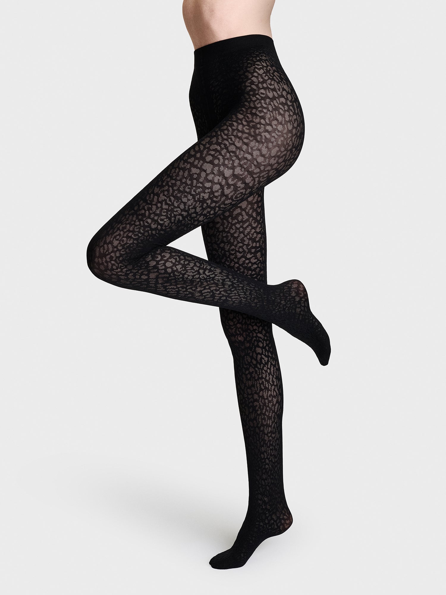 Elegant 50 denier tights featuring a stylized leopard pattern that extends to the waist. Crafted from a recycled polyamide-elastane blend, these patterned tights offer a sophisticated statement piece for the season. Pictured on a model
