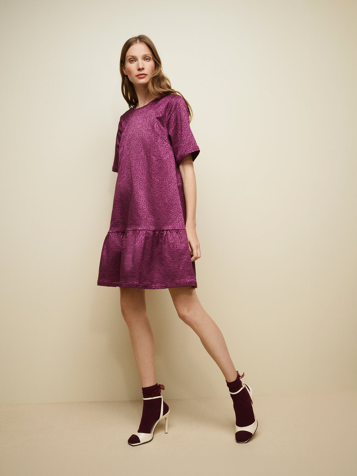 Nanso women's striking Leora dress captivates with its beautiful fabric, combining a festive sheen with a rich textured surface, pictured on a model with heels. | 36 - 175,5cm