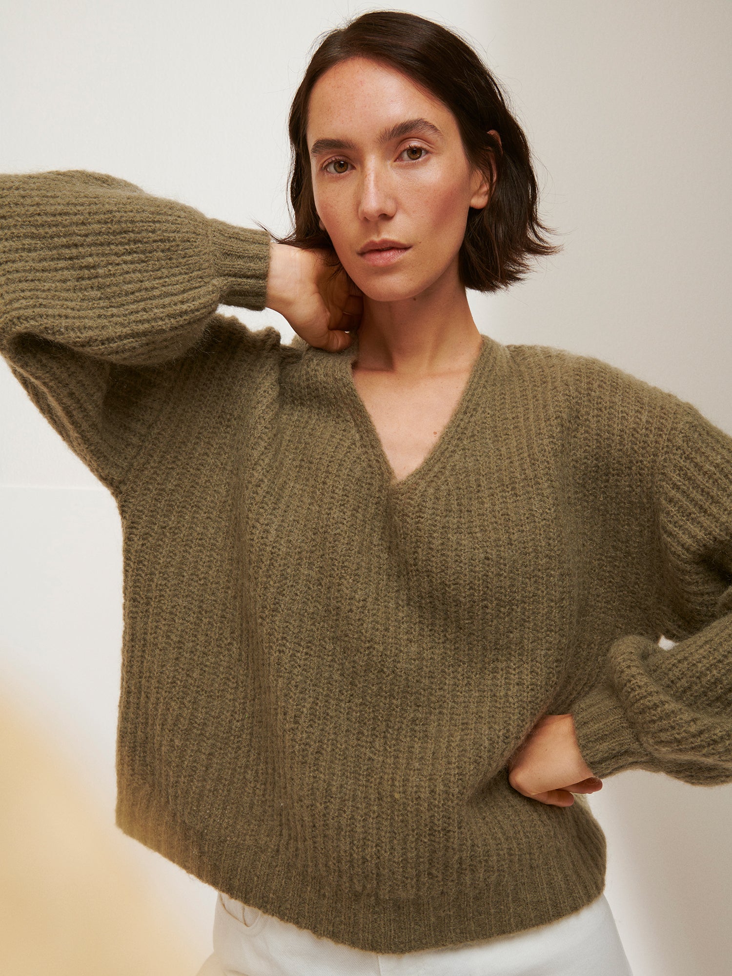 Woman wearing a green sweater against a plain background