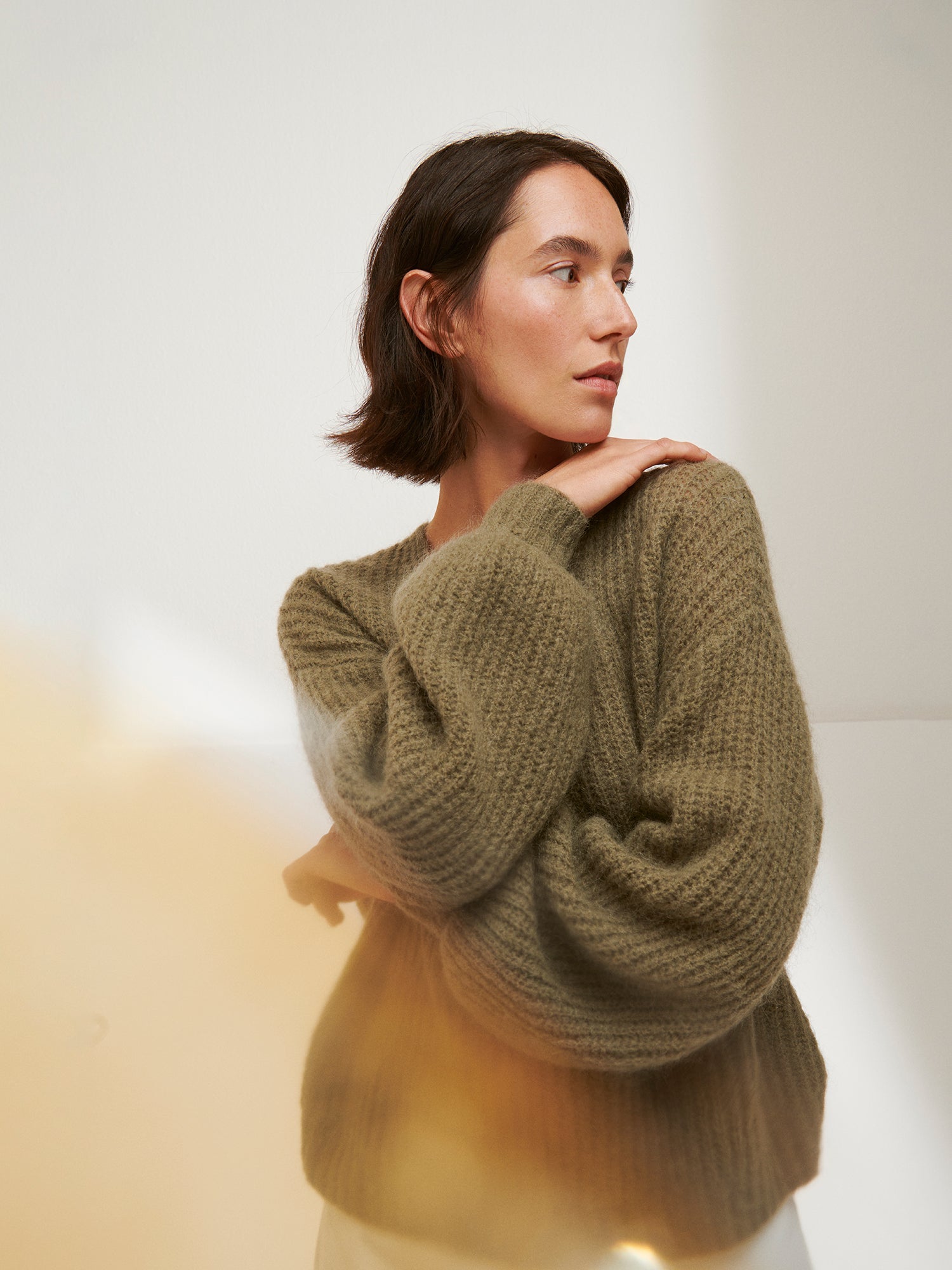 Woman wearing a green sweater against a plain background