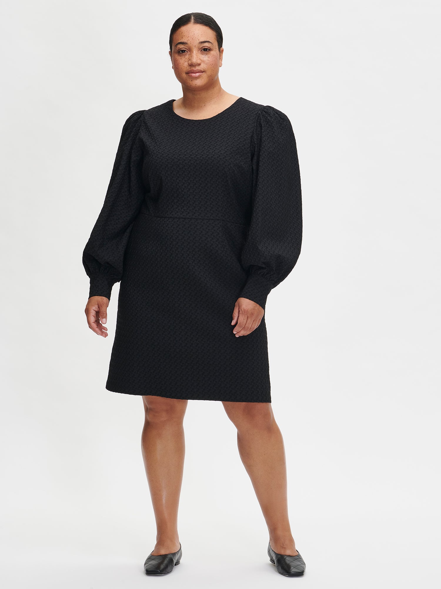 Nanso's elegant black Reliefi dress. On a model in size 46, front