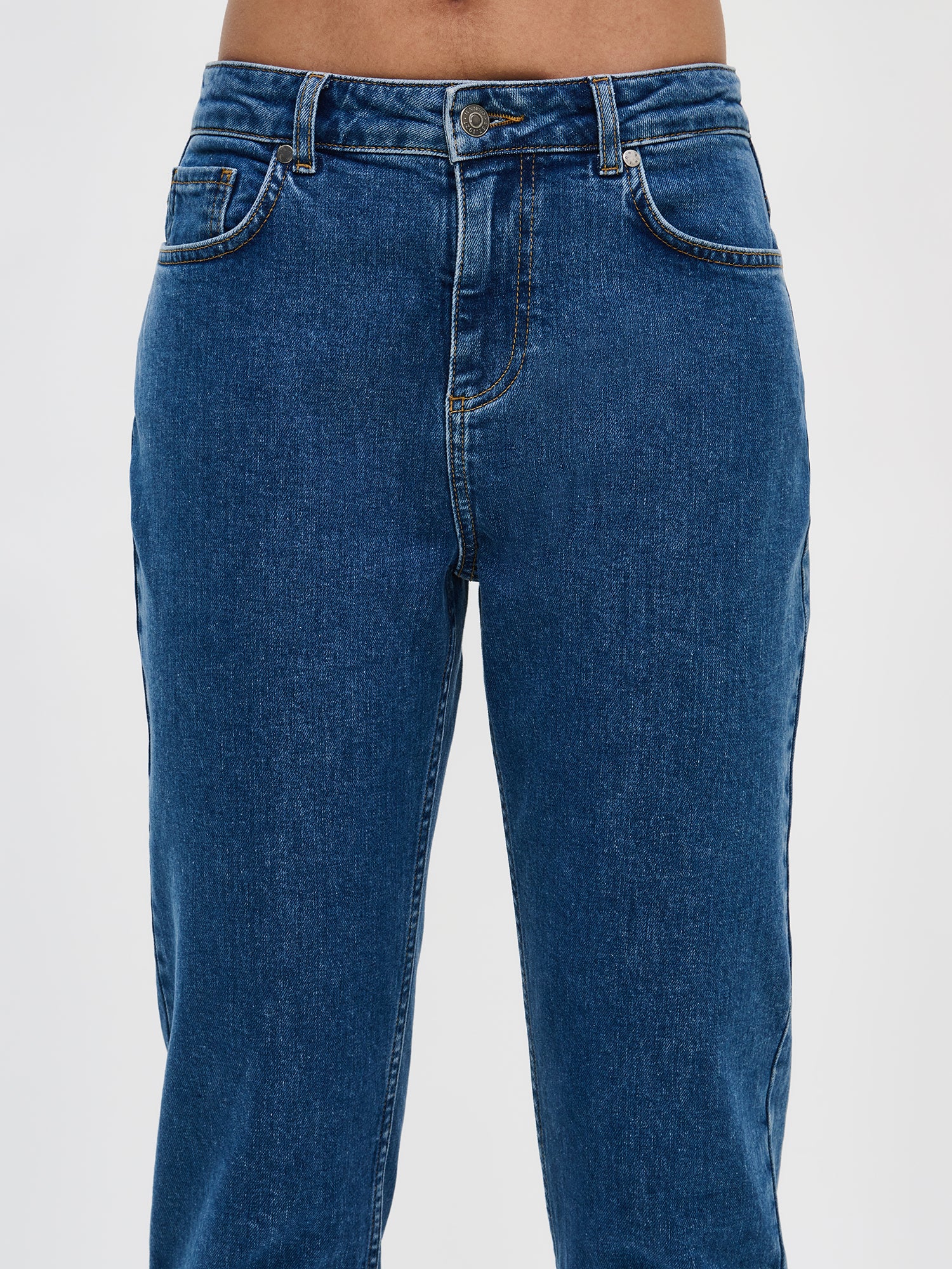 Nanso women’s comfortable cropped blue Fiilis jeans, close-up from the front. Waistband, button and zipper visible.