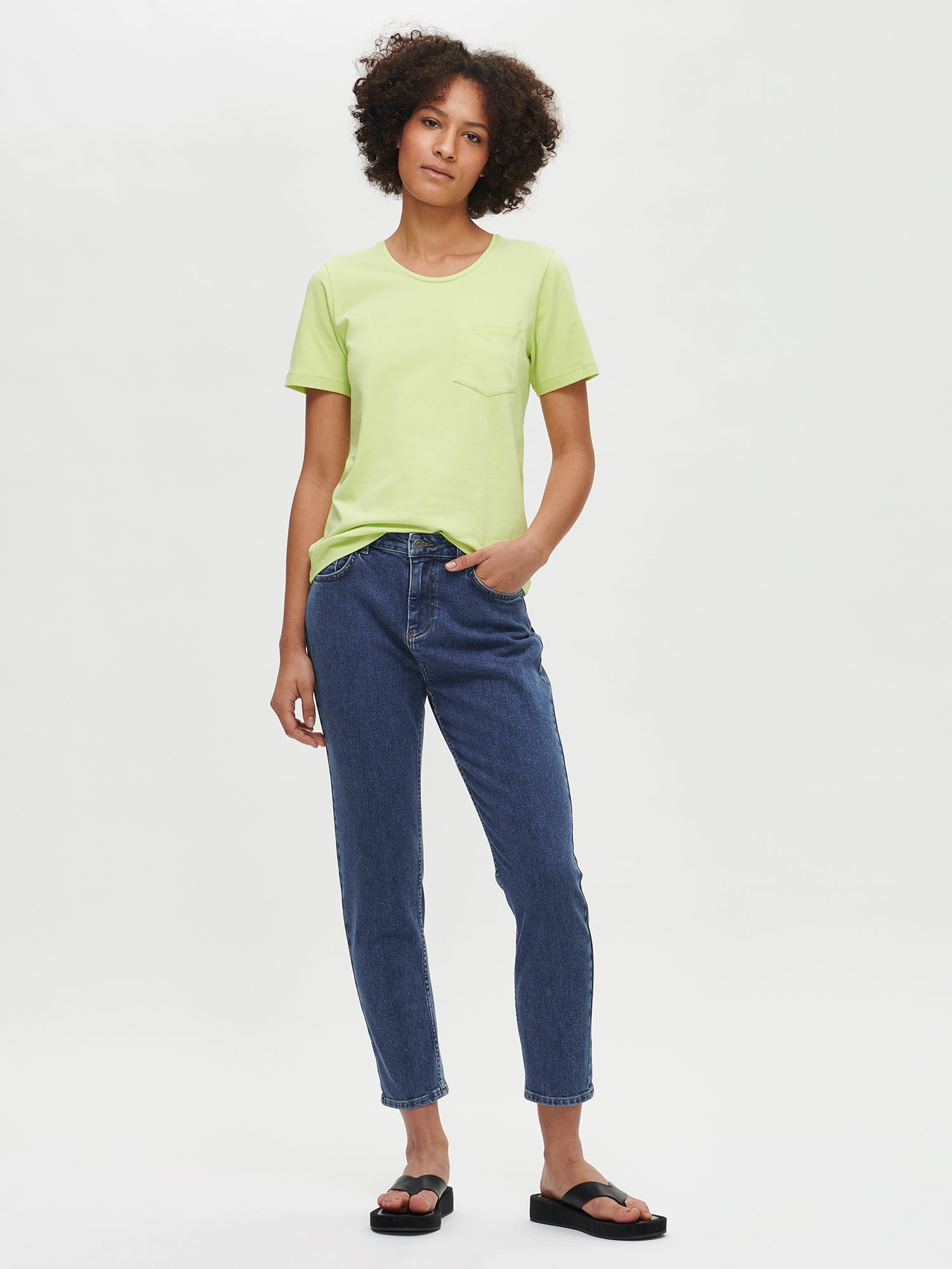 Nanso women’s comfortable cropped blue Fiilis jeans from the front on the model. Paired with a green Tasku T-shirt.