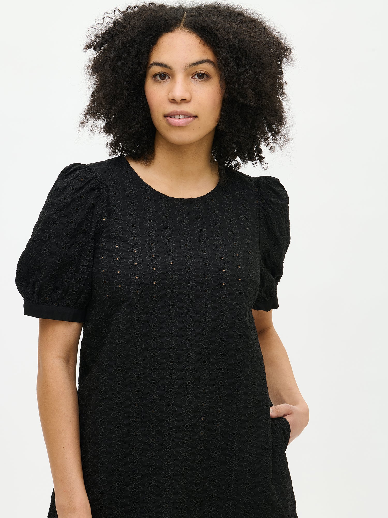 Nanso women's solid black Petra dress. The dress features 2/4-length sleeves that gather at the shoulder and above the cuff. In the picture, the dress is shown on a model in a close-up shot.