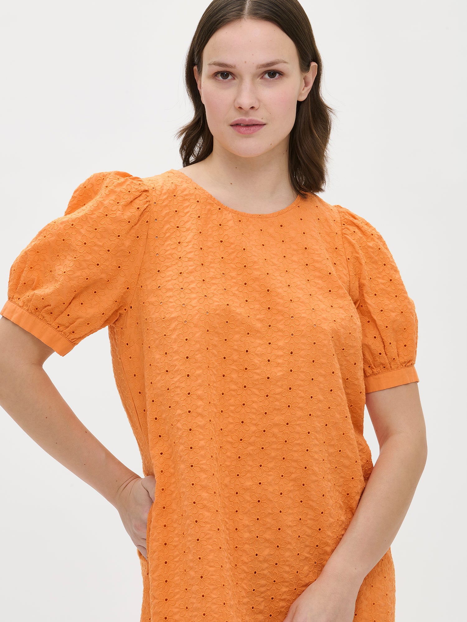 Nanso women's solid orange Petra dress. The dress features 2/4-length sleeves that gather at the shoulder and above the cuff. In the picture, the dress is shown on a model in a close-up shot.