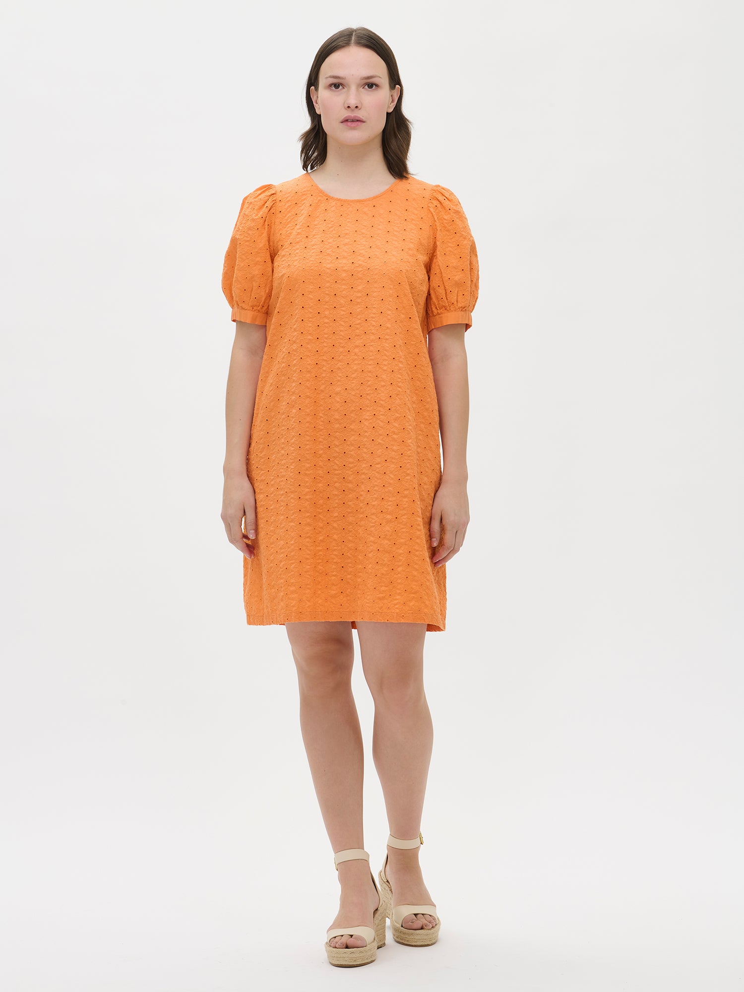 Nanso women's solid orange Petra dress with a hem that reaches above the knees. The dress features a round neckline finished with a trim and bust darts. Shown in the image on a model from the front.