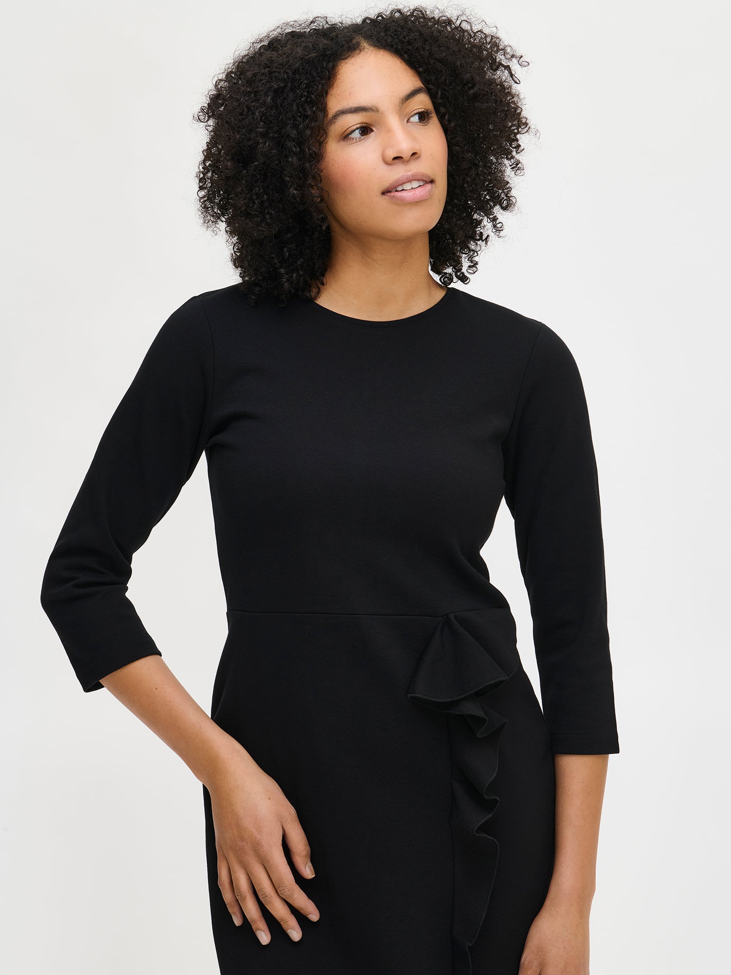 Nanso women’s black Opera dress, fitted knee-length design with round neckline and frill detail at slit, worn by model in close-up photo.