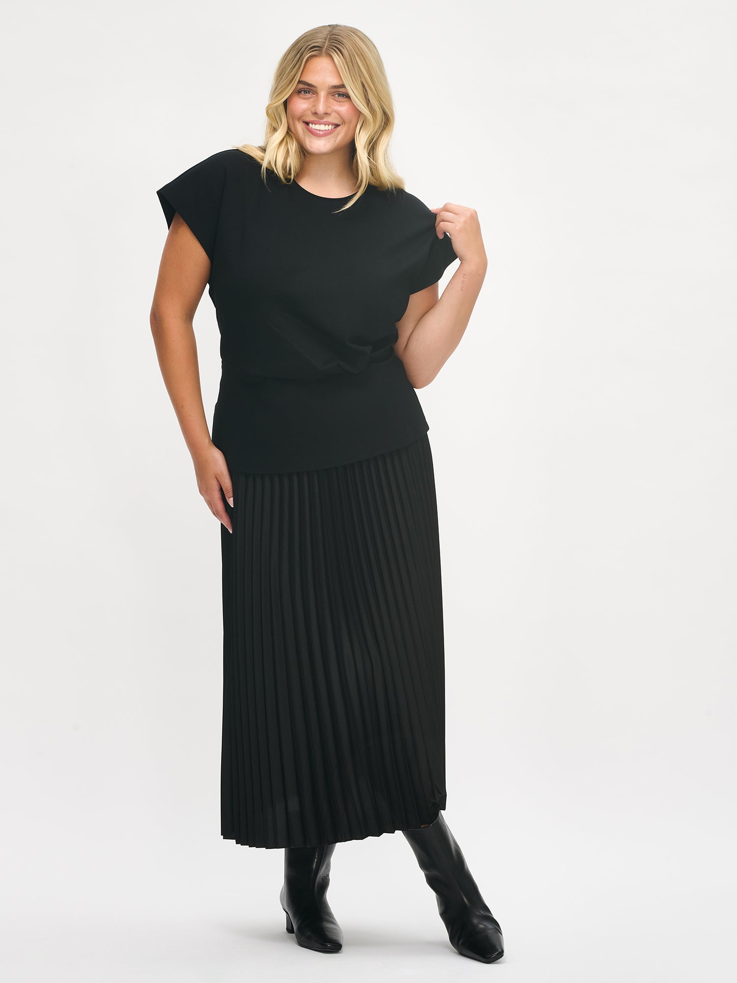 Nanso women’s Elegia blouse – timeless Finnish design in soft black knit with cap sleeves and pleated waist. Image from the front, in size XL.