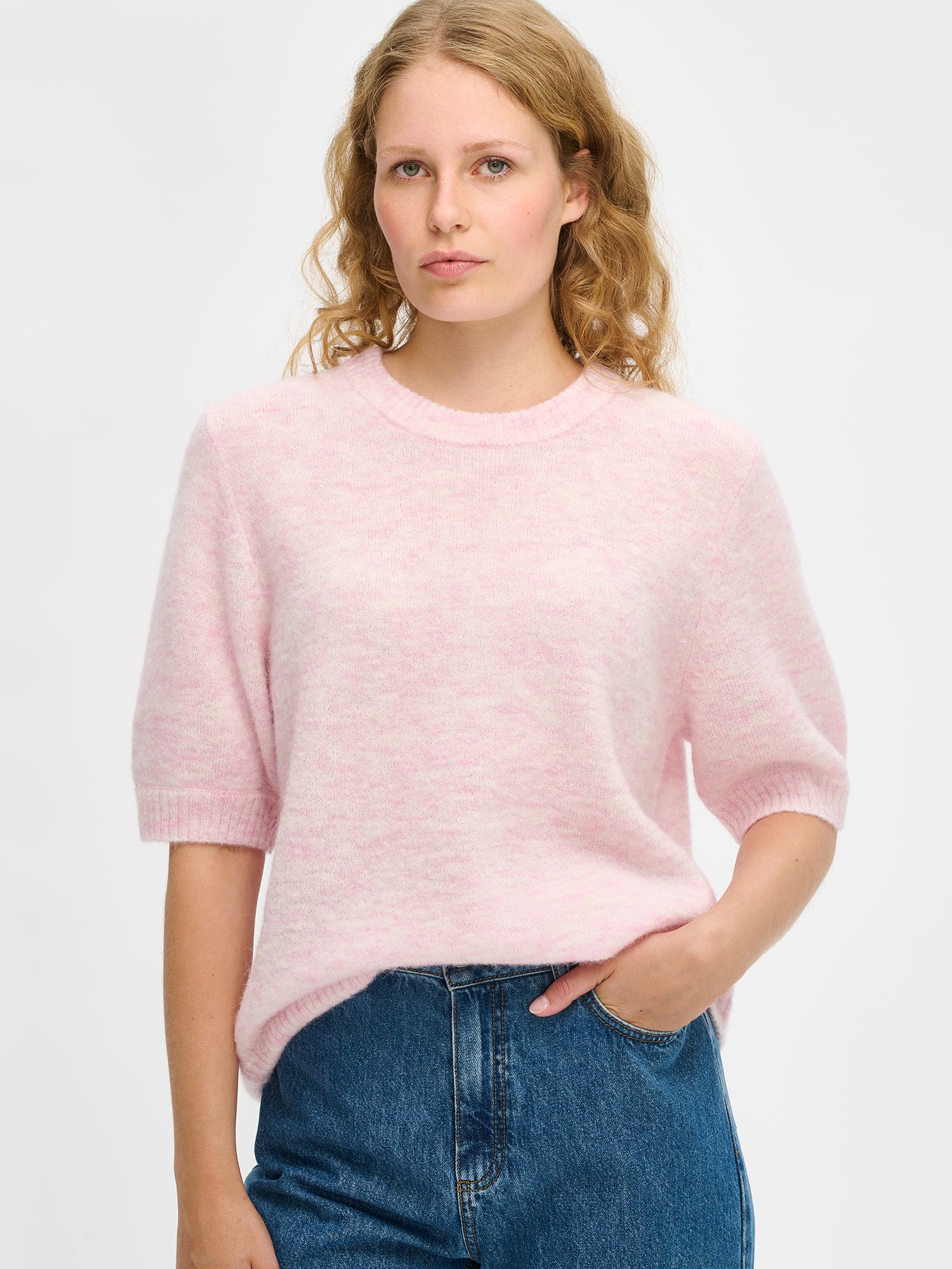 Nanso Women’s Tuohi knit sweater in pink, soft knit that falls beautifully to the hips, round neckline and short half sleeves, worn by model in close-up photo.