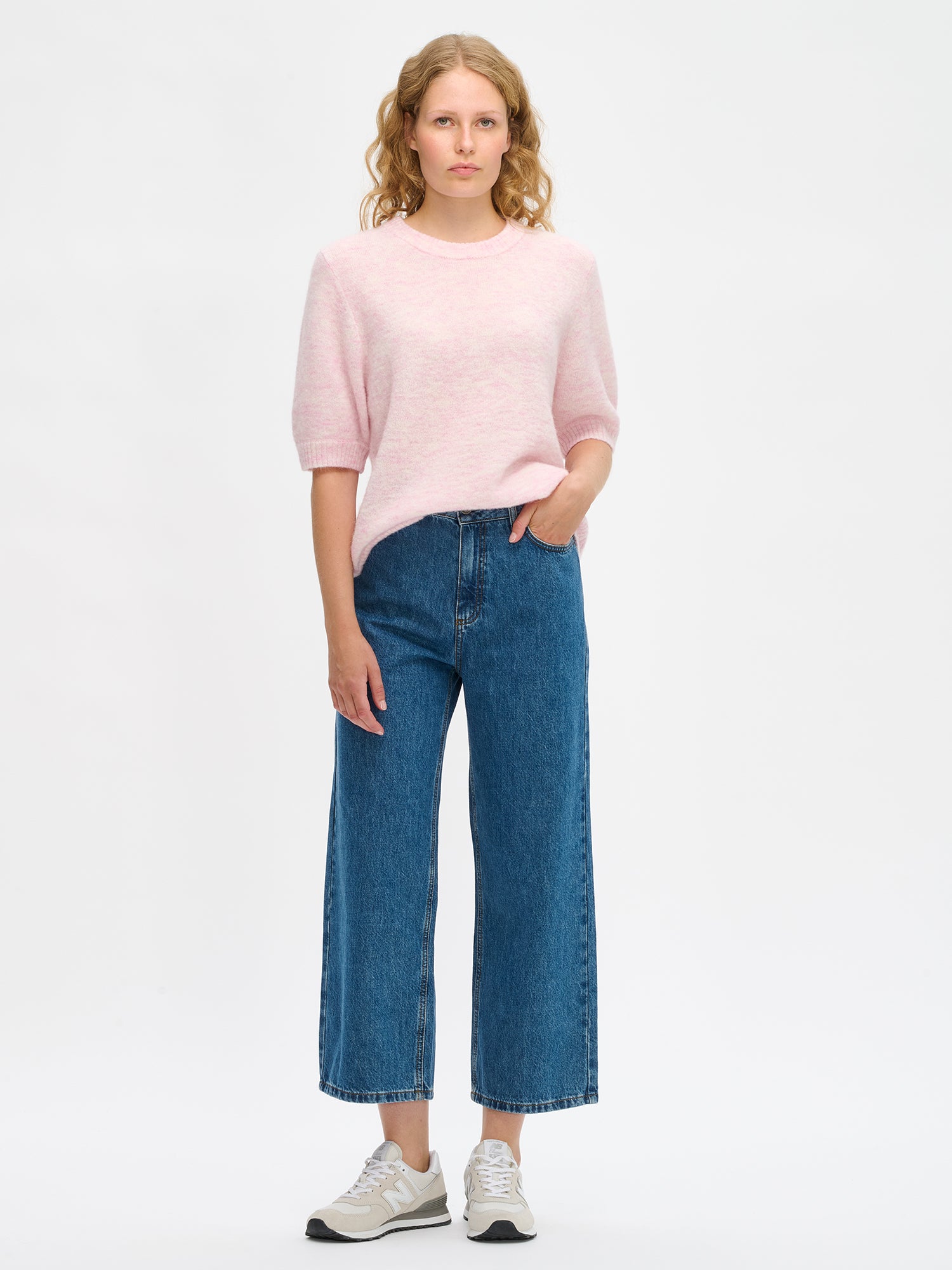 Nanso Women’s Tuohi knit sweater in pink, relaxed fit, hip-length design with round neckline and short half sleeves, worn by model in full-body photo.