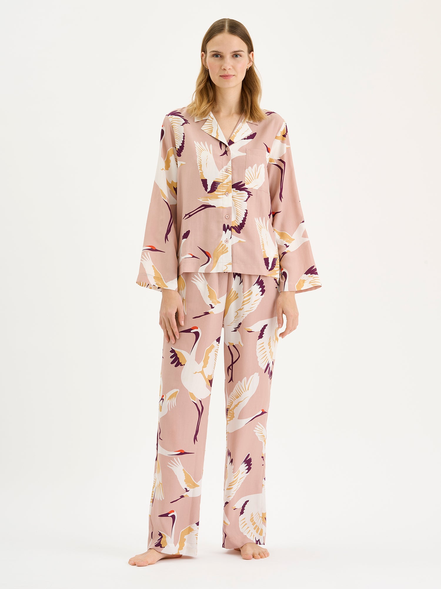 Women's elegant Kurki pajama shirt in a beautiful and striking pale pink print, on a blonde model with matching pants.