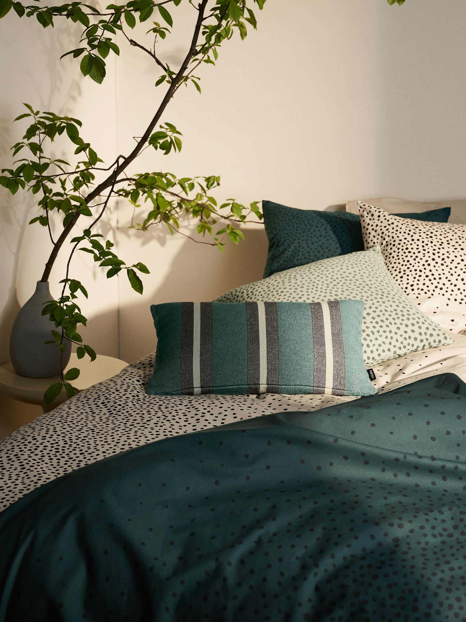 Täplä duvet cover set in dark green and beige with charming dots, in a cosy home decor picture.