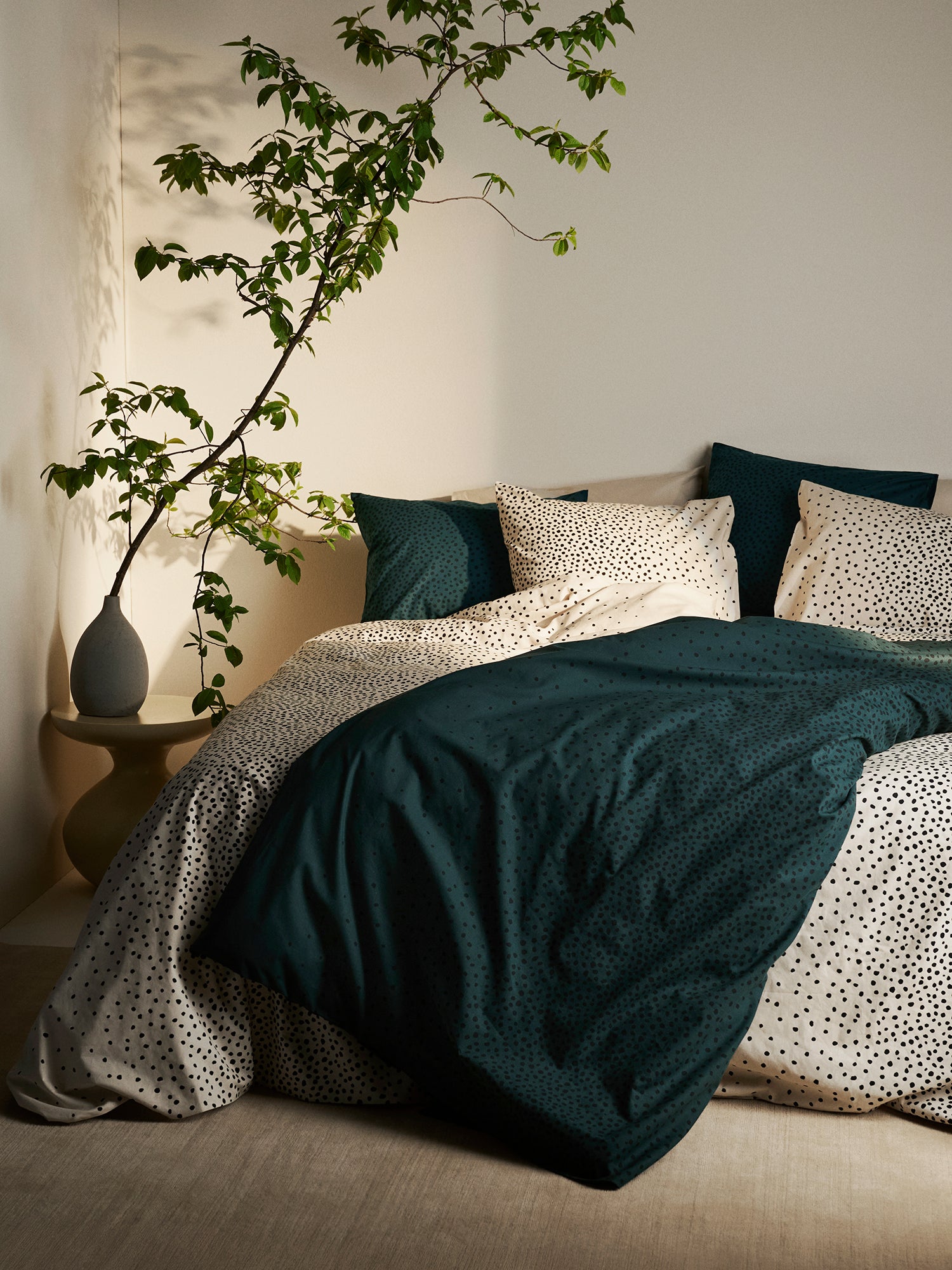 Täplä duvet cover set in dark green and beige with charming dots, in a cosy home decor picture.