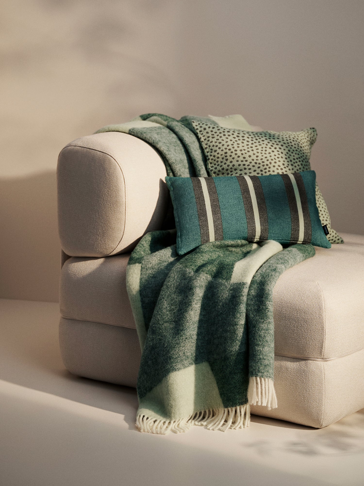 A beautiful home decor setting with green toned decorative throw pillows and a blanket.