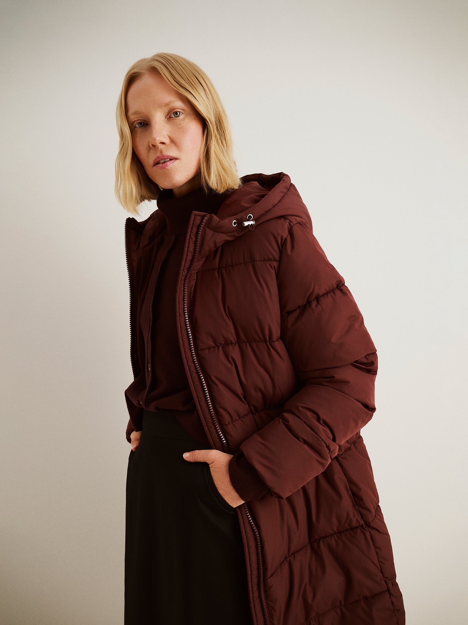 The Lumi Long Pink Puffer Coat in beige offers cozy warmth with its lightweight, puffy insulation.
