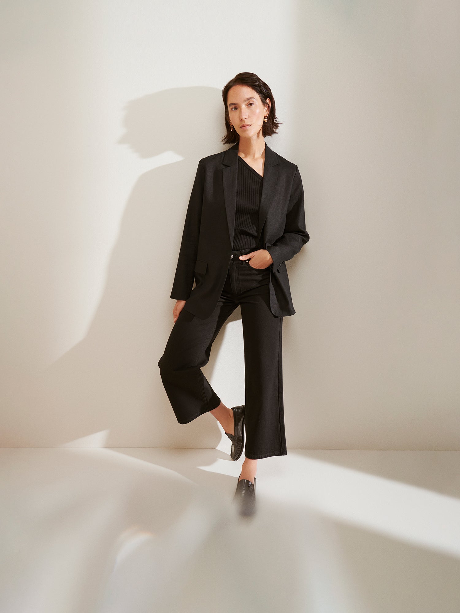 The model is wearing a stylish black ARLES linen blazer for women, paired with jeans.