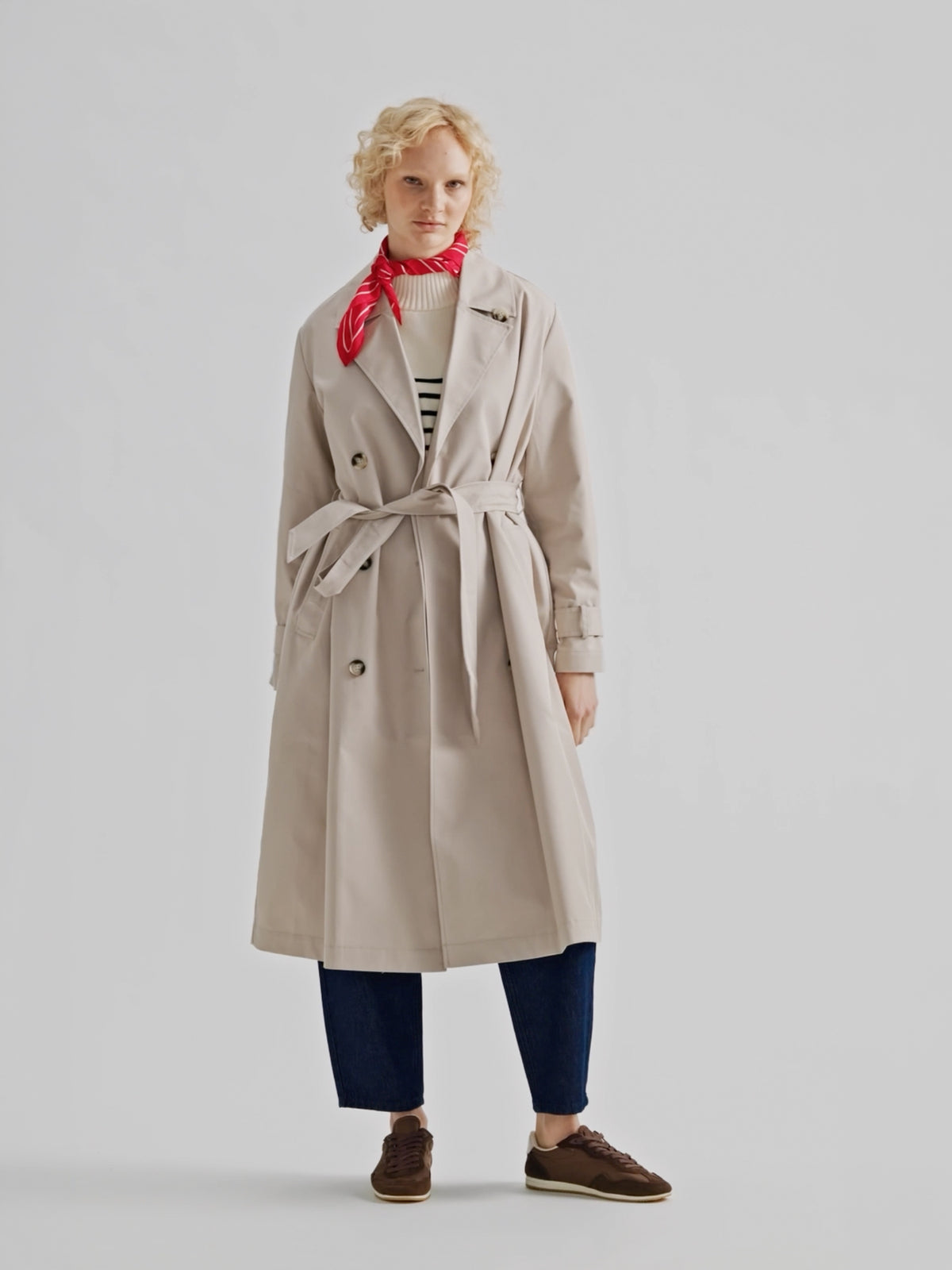 A timeless Beige trench coat on a model with blue jeans