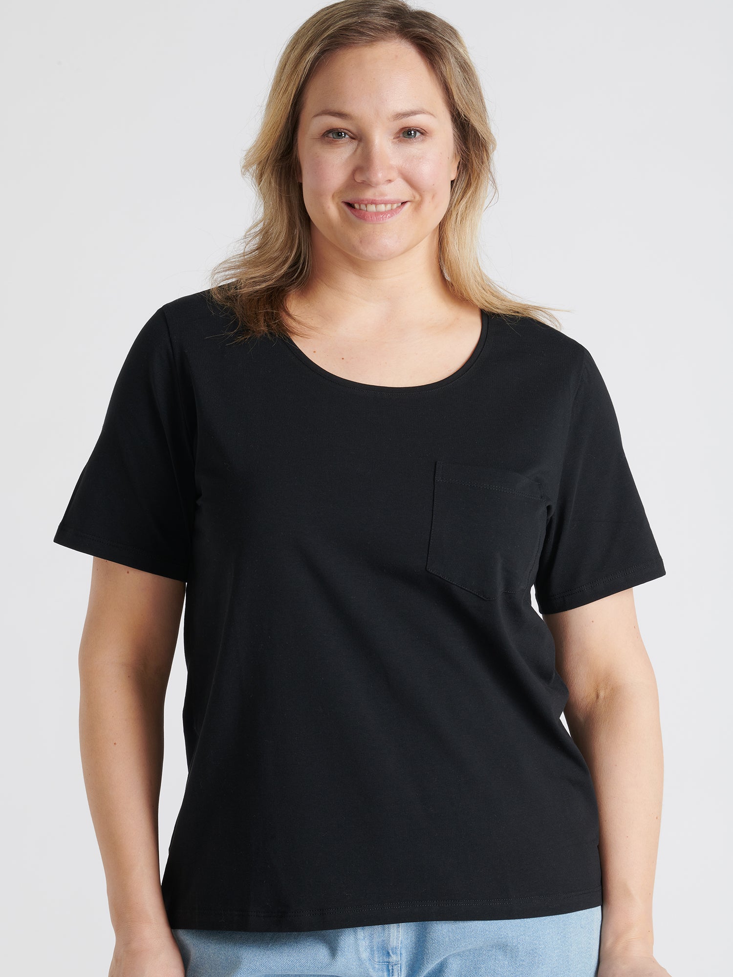 This elegant black Tasku t-shirt for women features a round neckline. A classic t-shirt is a reliable choice for any outfit, with its effortless versatility. Worn by a model in size L.