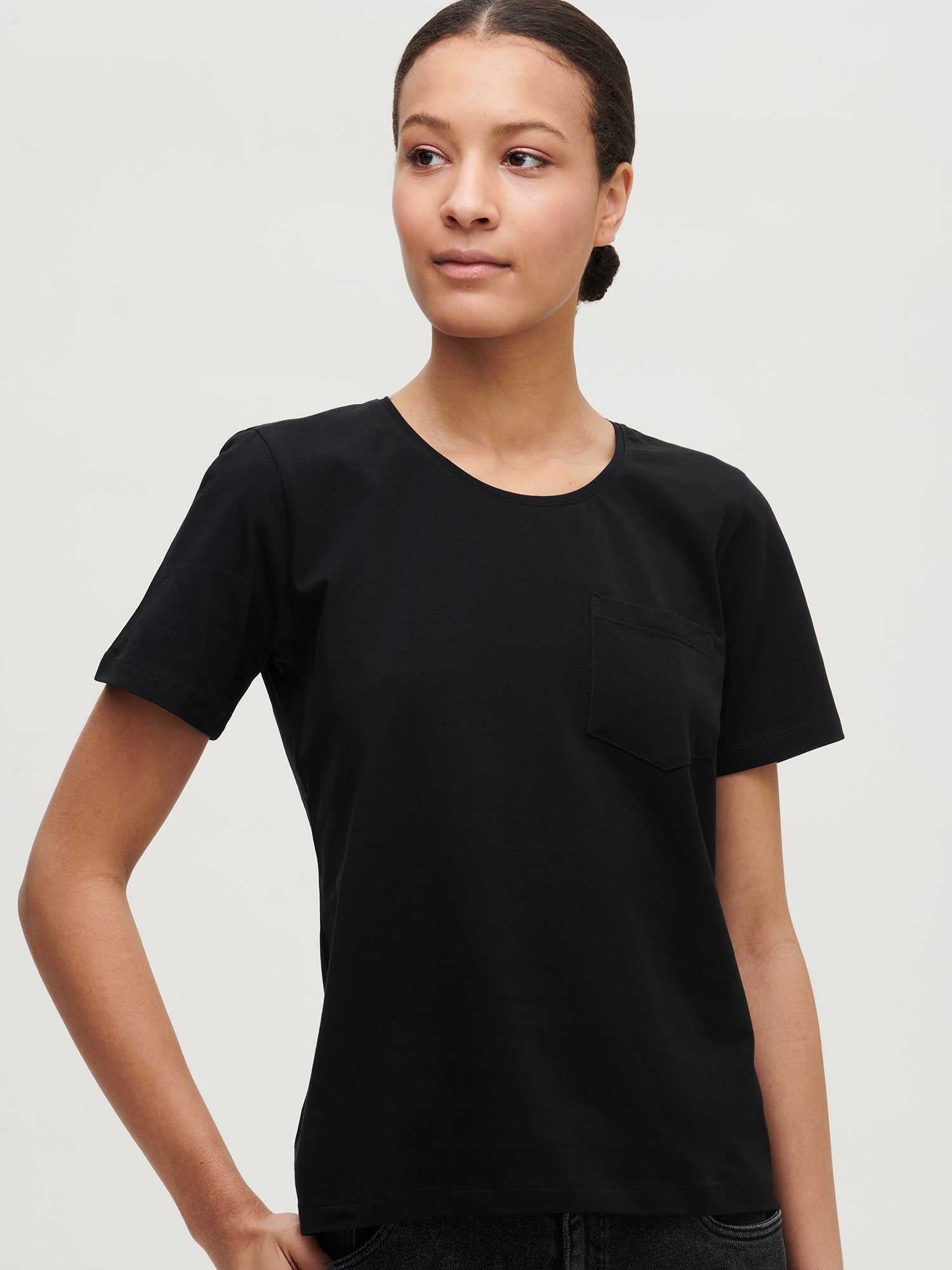 This elegant black Tasku t-shirt for women features a round neckline. A classic t-shirt is a reliable choice for any outfit, with its effortless versatility. Worn by a model in size S.