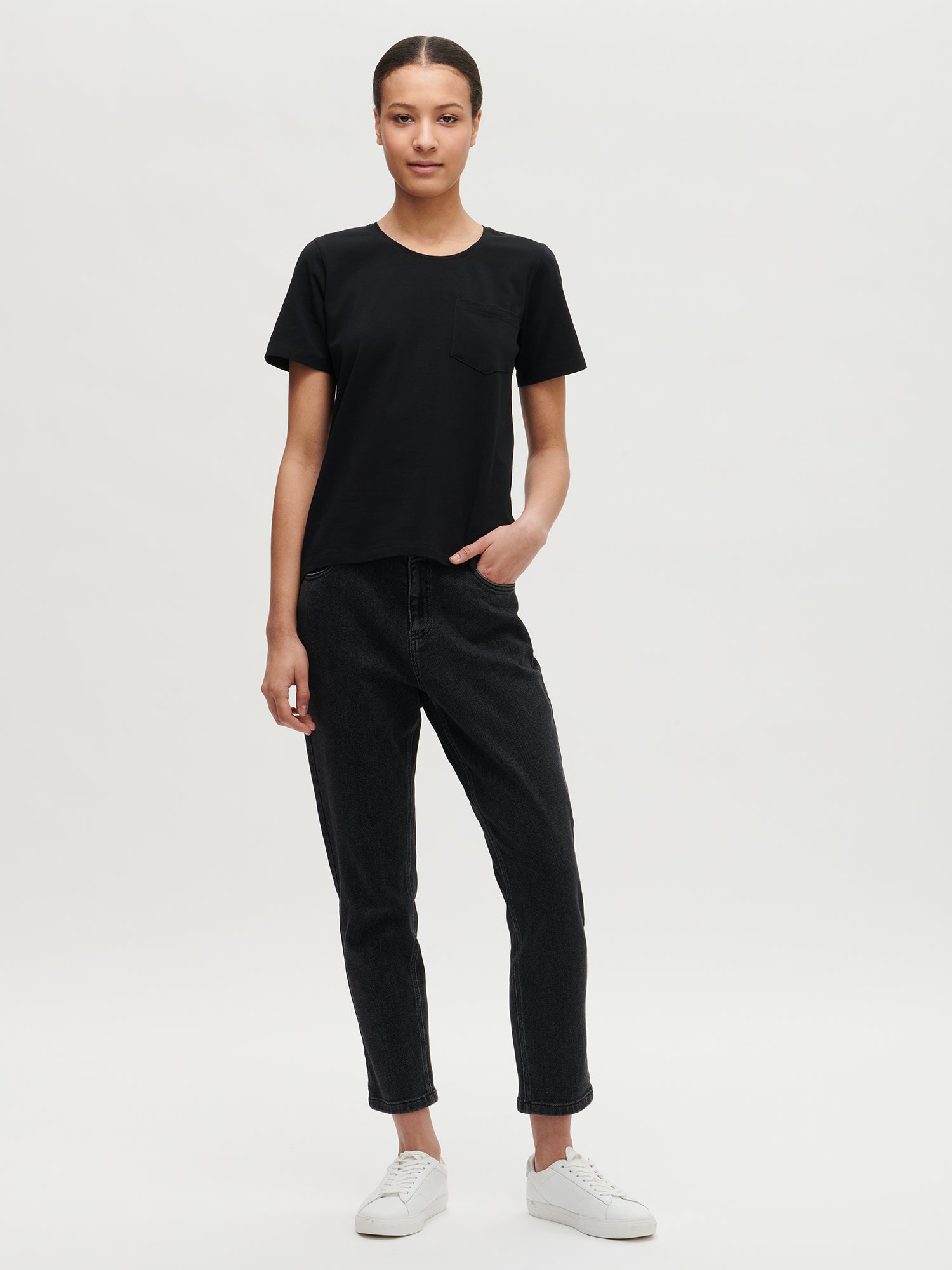 This elegant black Tasku t-shirt for women features a round neckline. A classic t-shirt is a reliable choice for any outfit, with its effortless versatility. Worn by a model in size S.
