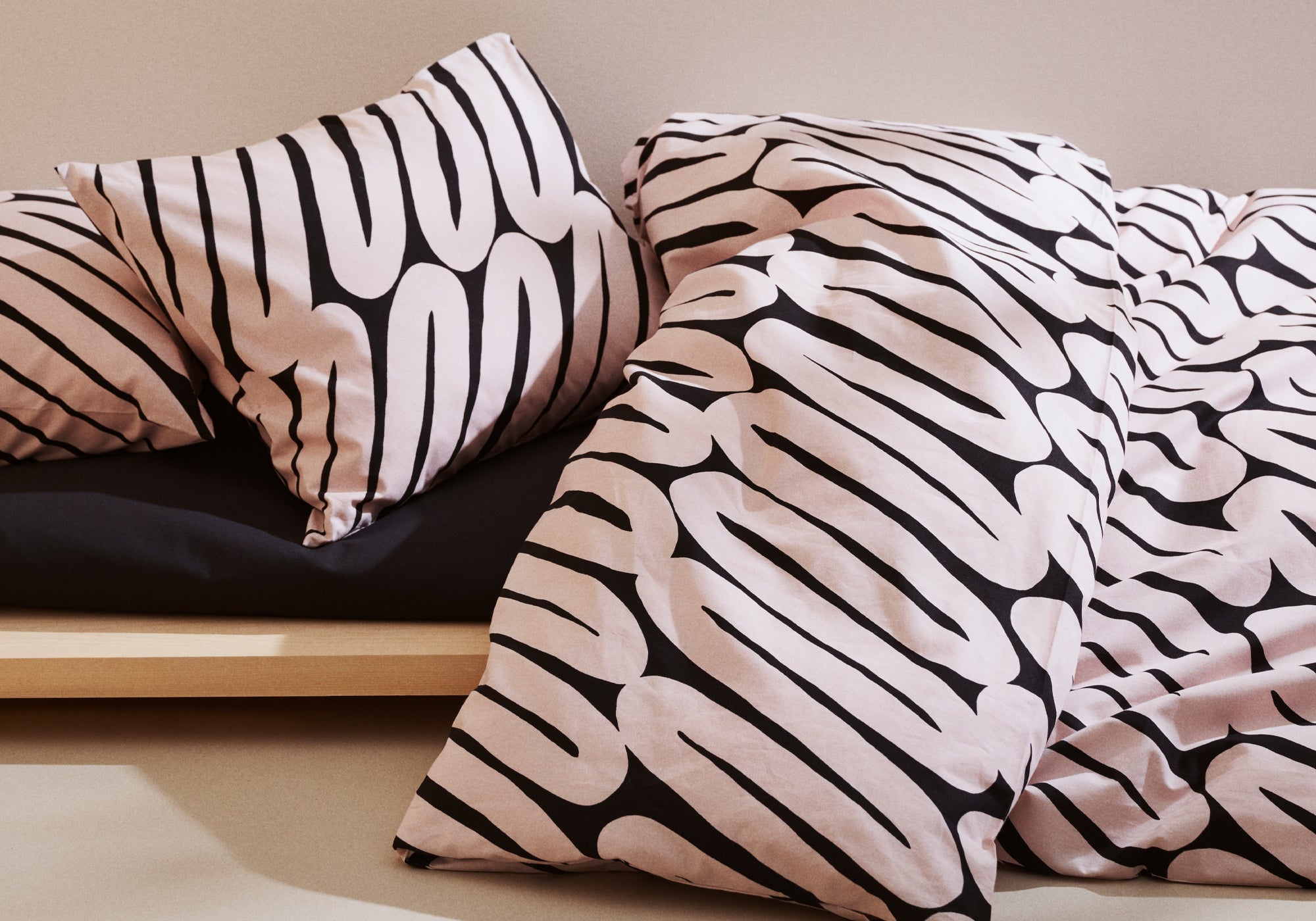 Laskos black and beige patterned pillows and duvet on a bed