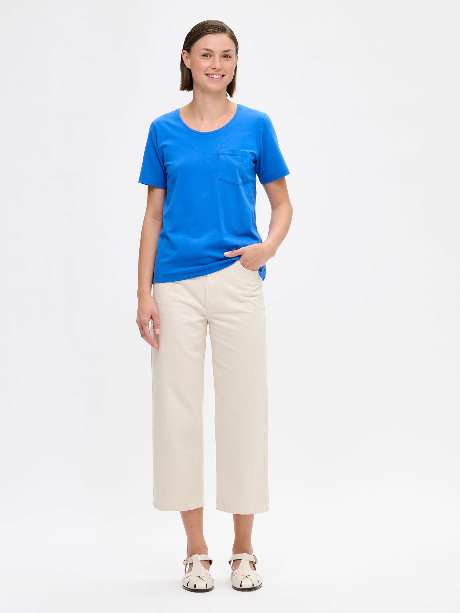 This blue Tasku t-shirt for women features a round neckline. A classic t-shirt is a reliable choice for any outfit, with its effortless versatility. Pictured on a model from the front.