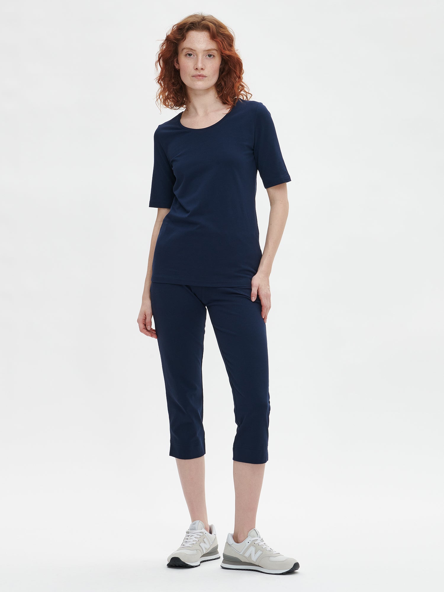 Ladies' Basic 7/8 dark blue jersey bottoms with a comfortable elastic band at the waist, side pockets and small side slits at leg openings. On a model pictured from the front with a dark blue t-shirt.