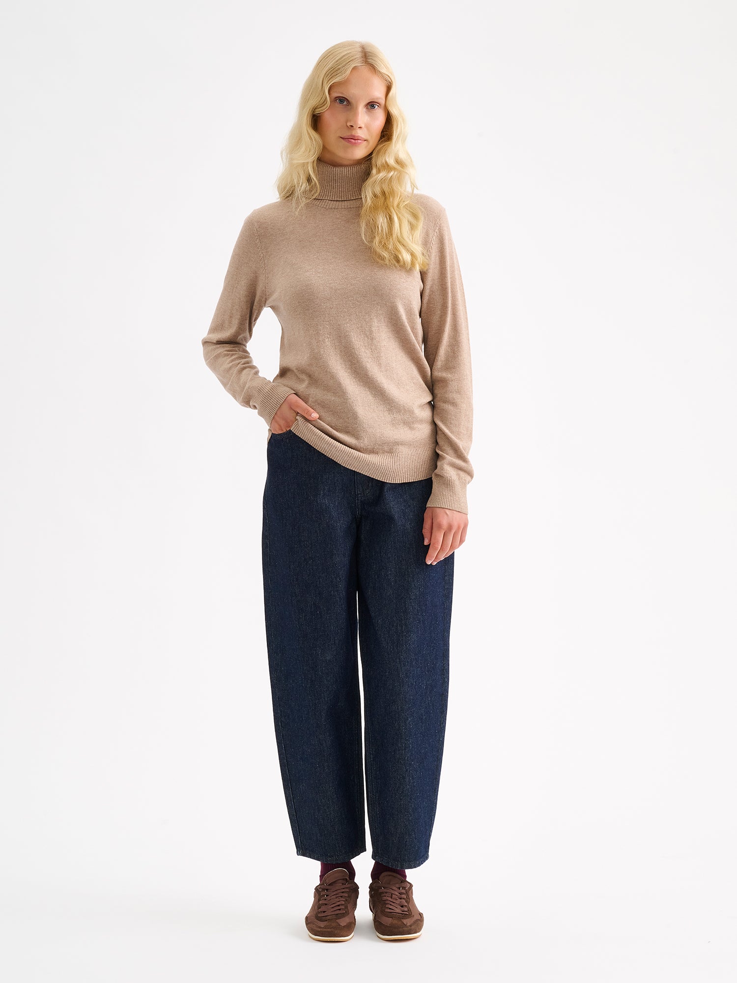 Nanso women’s stylish and lightweight beige Villis turtleneck sweater on a model with jeans.