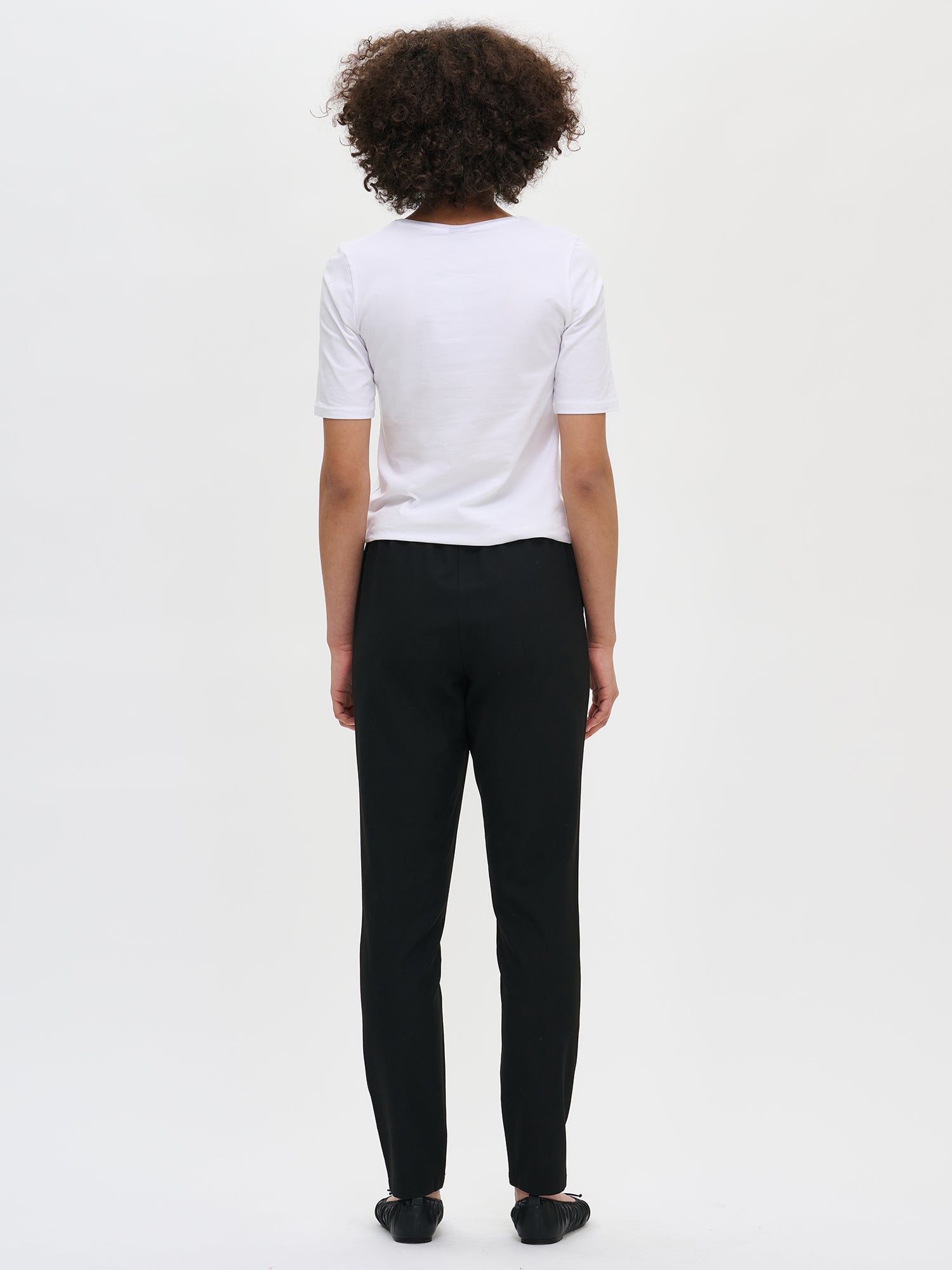 Nanso women's black Joggeri trousers with pockets and elastic waistband, on a model from the back.