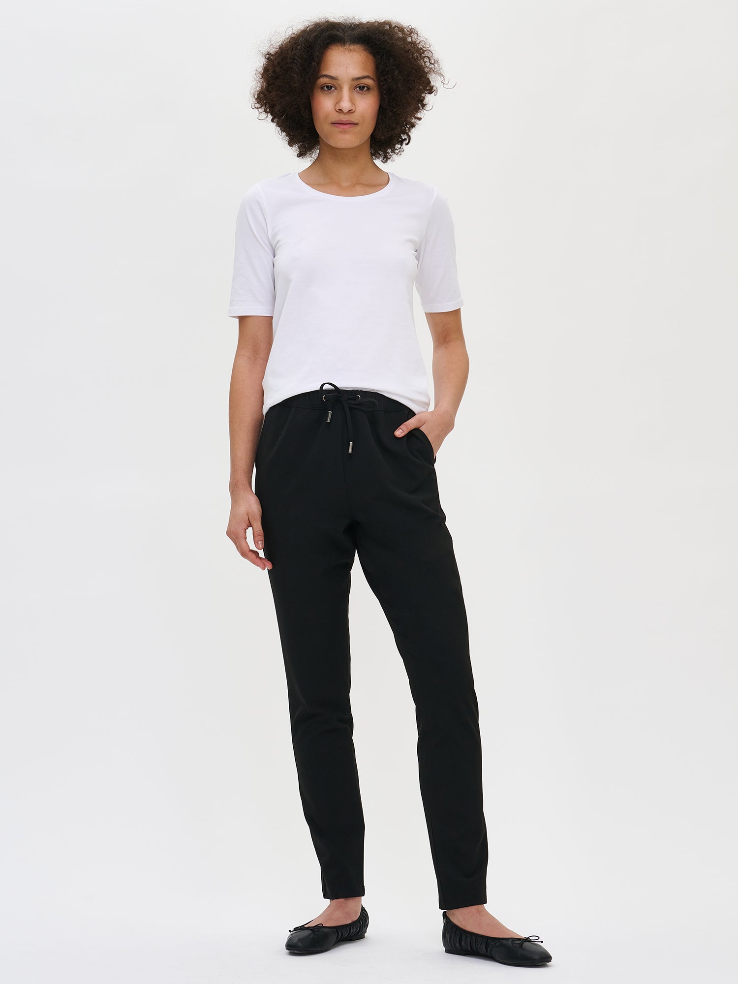 Nanso women's black Joggeri trousers with pockets and elastic waistband, on a model from the front.