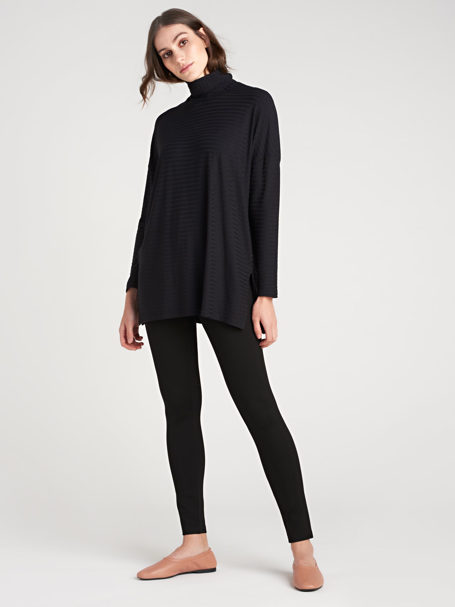 Nanso women's narrow black Fanni trousers feature a comfortable elastic waistband, full-length legs and four darts at the front and two at the back for a flattering silhouette. On a model pictured from the front.