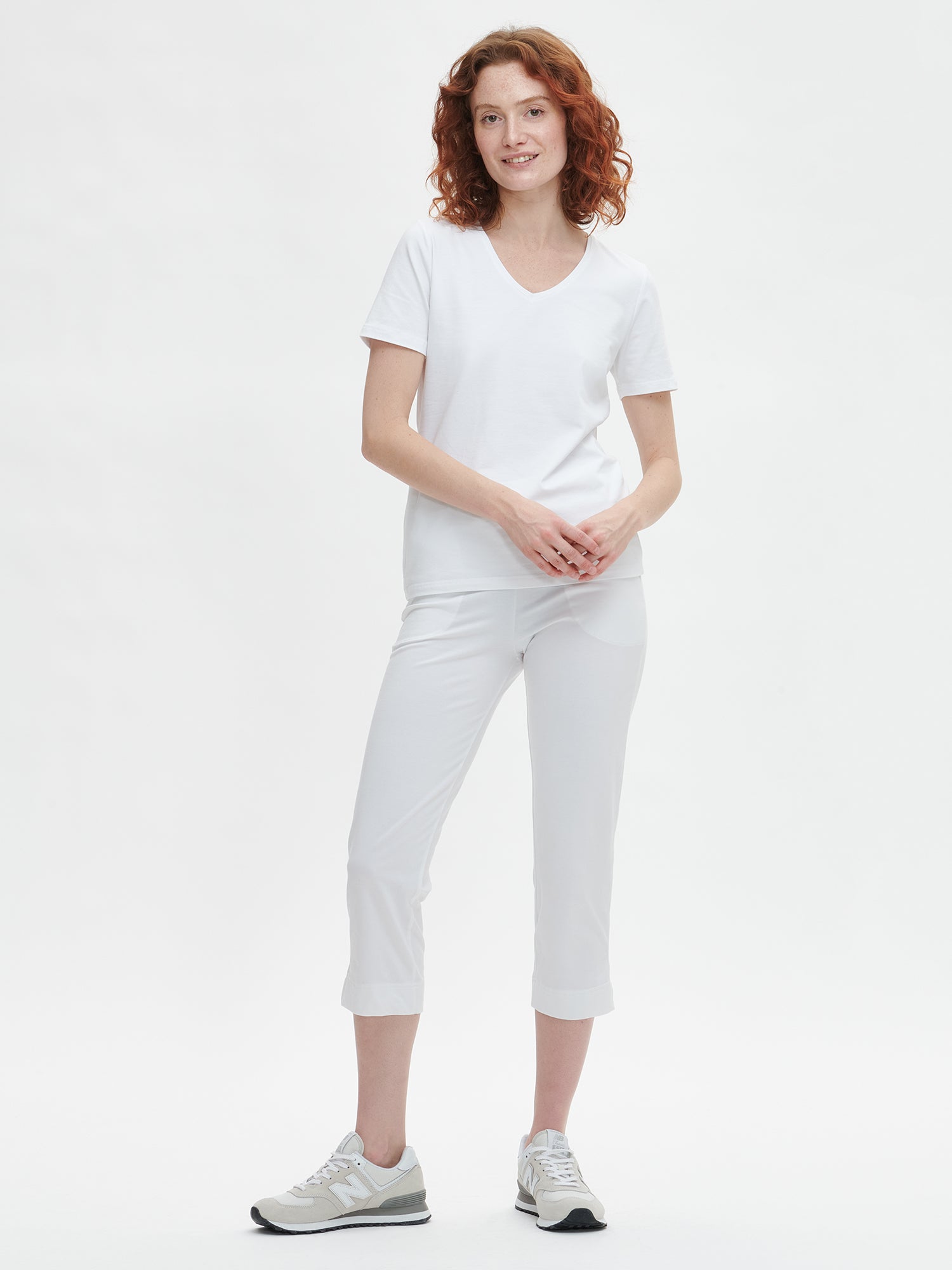 Women's Basic white T-shirt features a flattering V-neckline and comfortable short sleeves made from stretchy organic cotton-elastane blend, on a model pictured from the front.