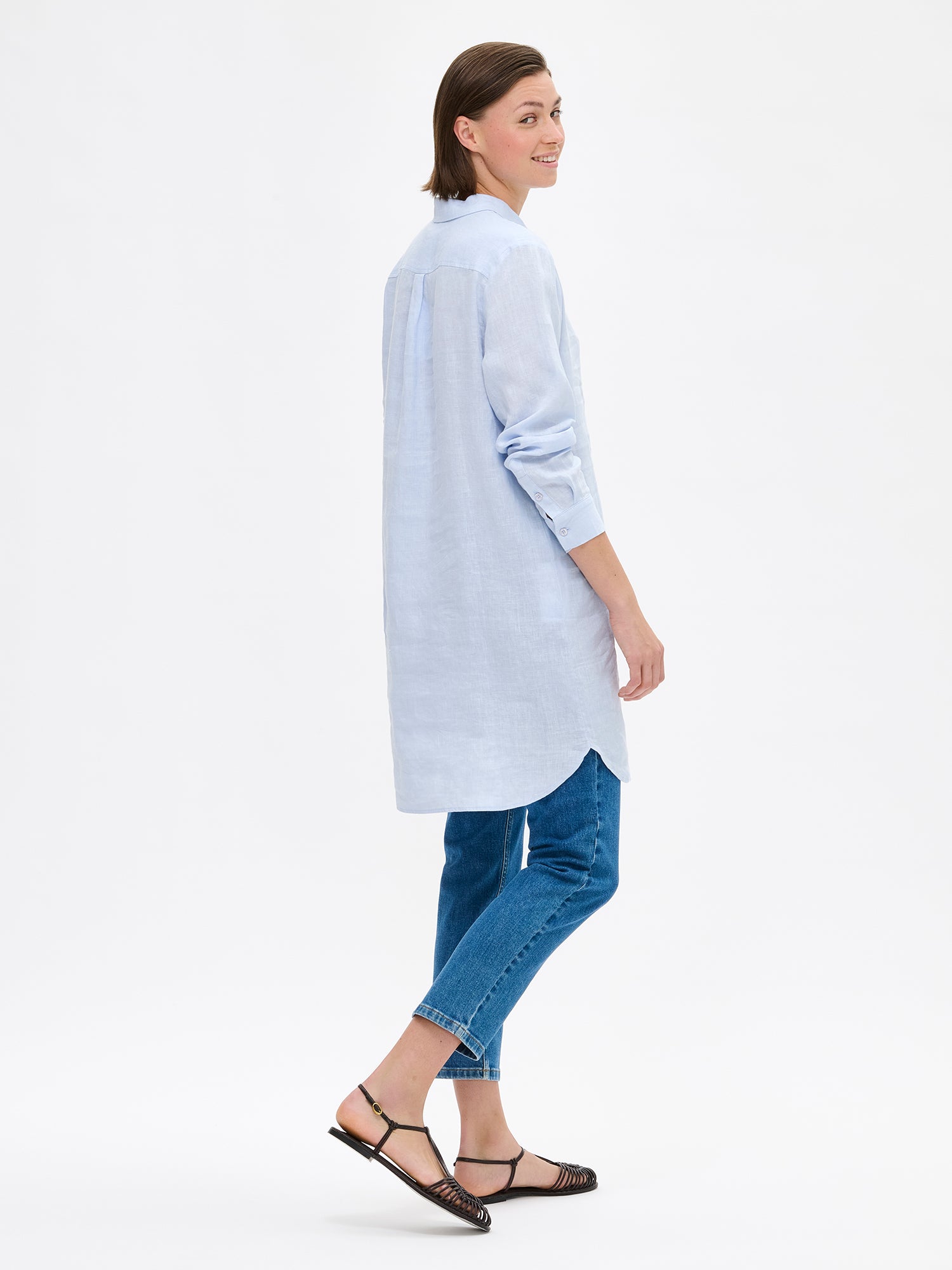Nanso's long PELLAVA shirt in light blue on a model with jeans, photographed from the side angle.