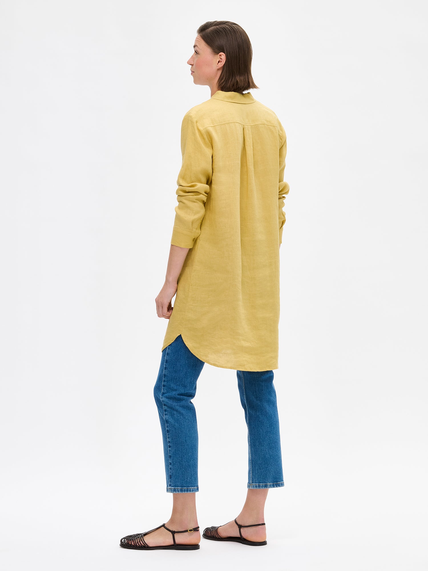 Nanso's long PELLAVA shirt in yellow on a model with blue jeans pictured from the side.