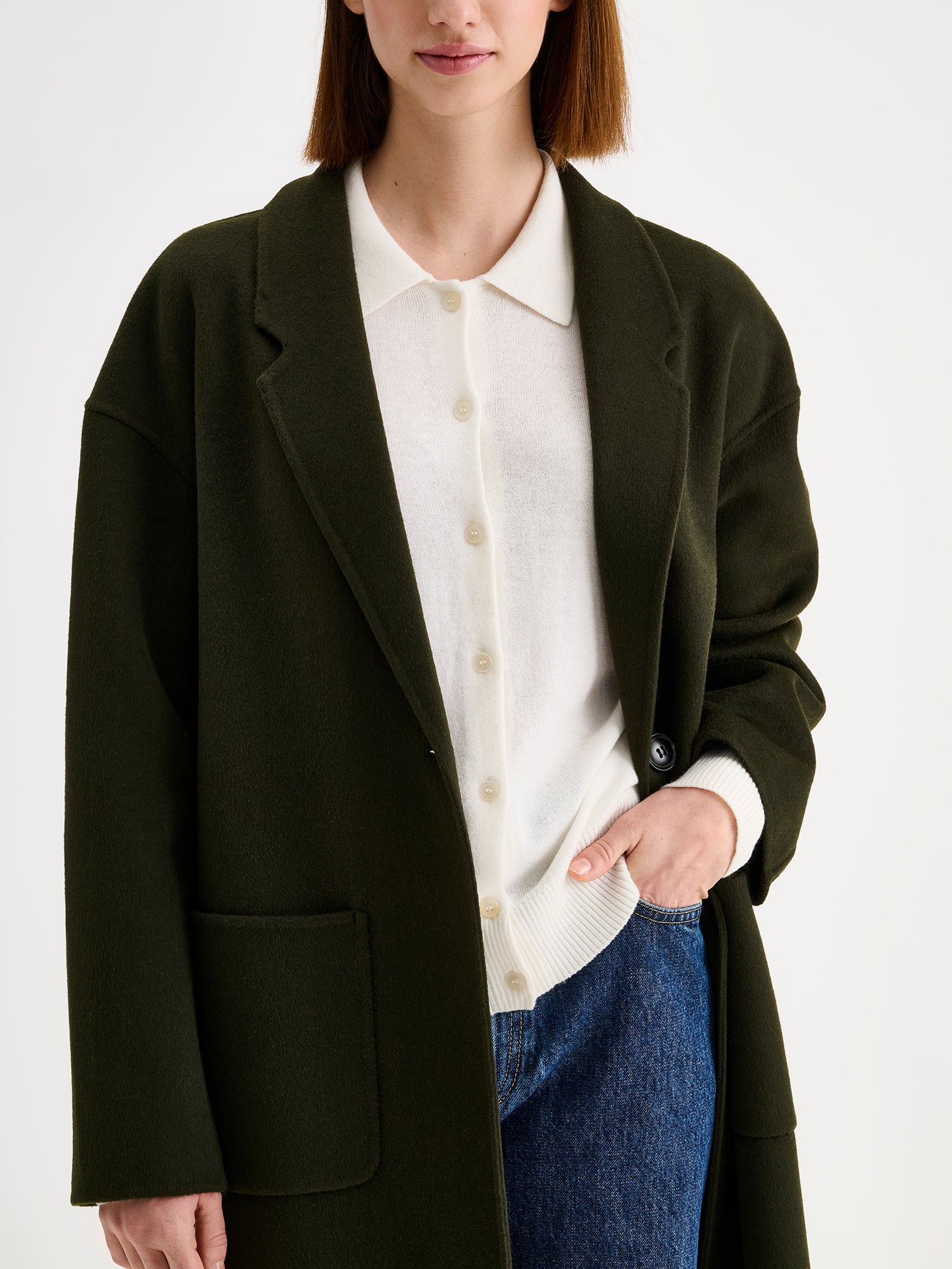 Nanso women's stylish and timeless olive green YLLE wool coat on a model with a white collared cardigan and jeans