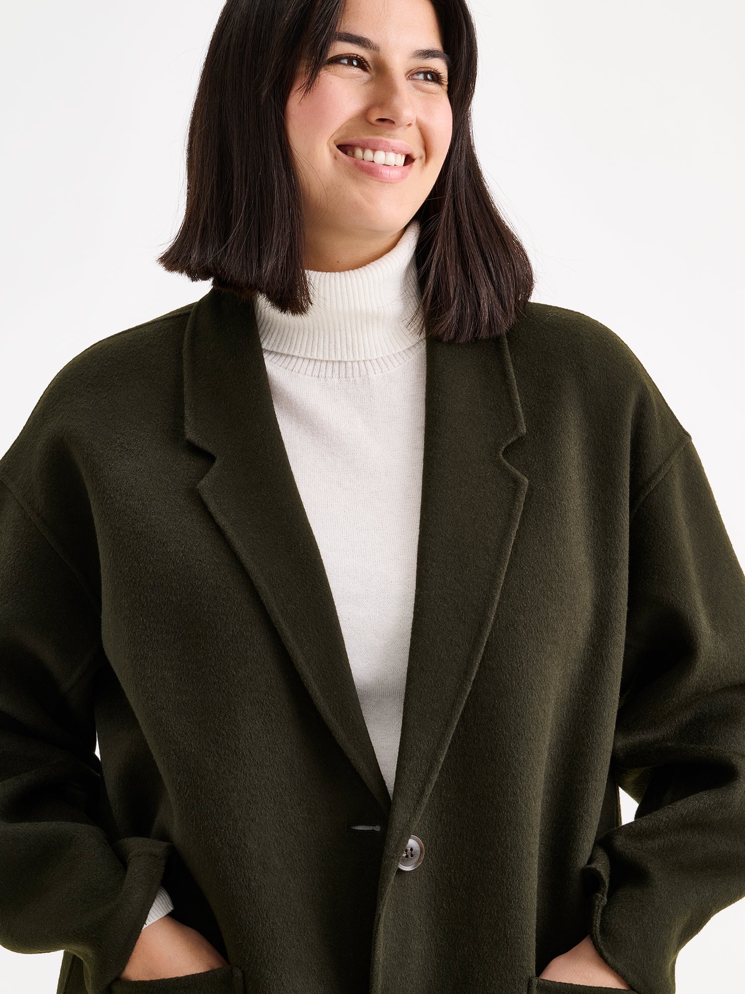 Nanso women's stylish and timeless olive green YLLE wool coat on a model with a white turtle neck close-up