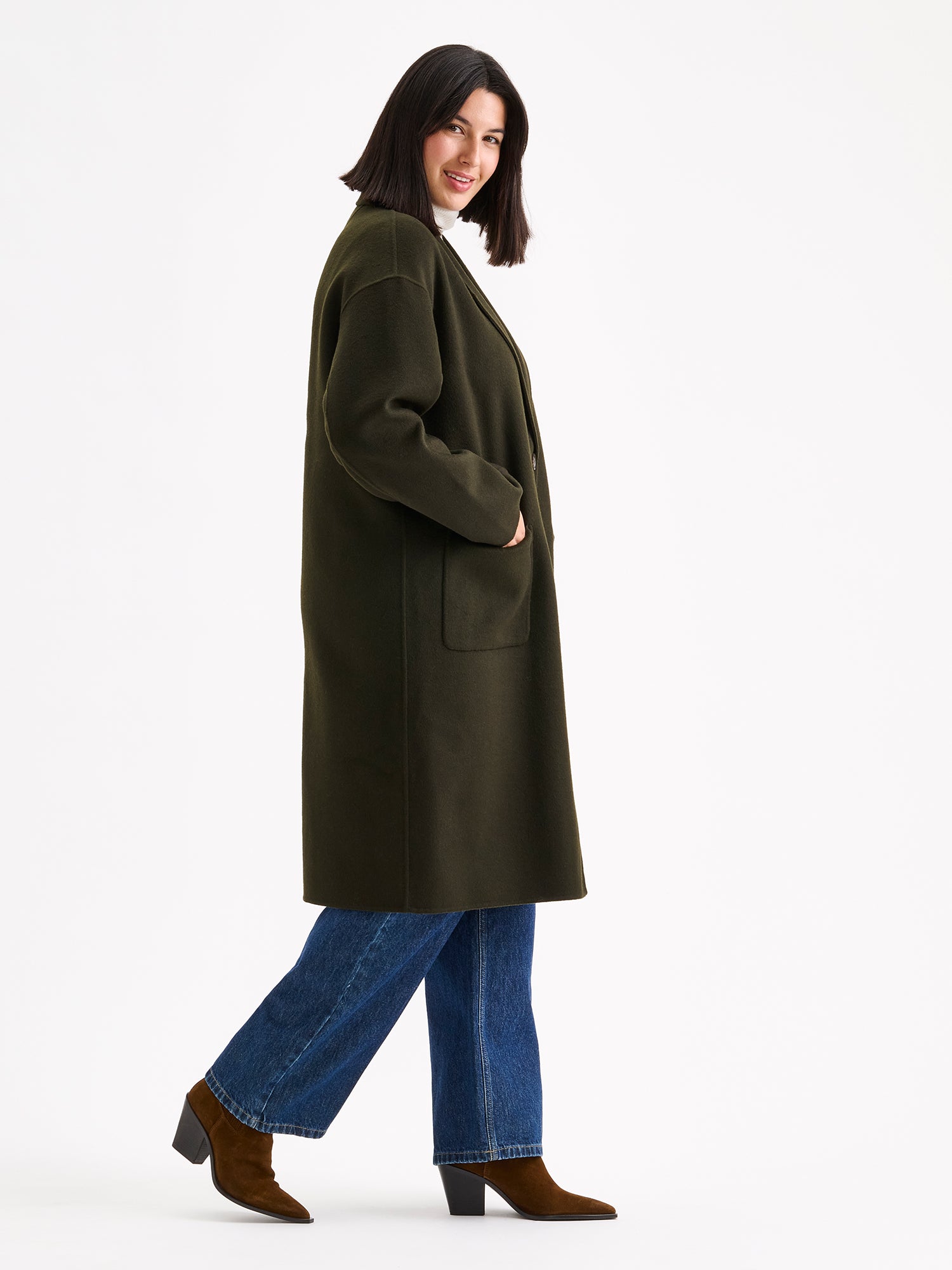 Nanso women's stylish and timeless olive green YLLE wool coat on a model with a white turtle neck and jeans, from the side angle
