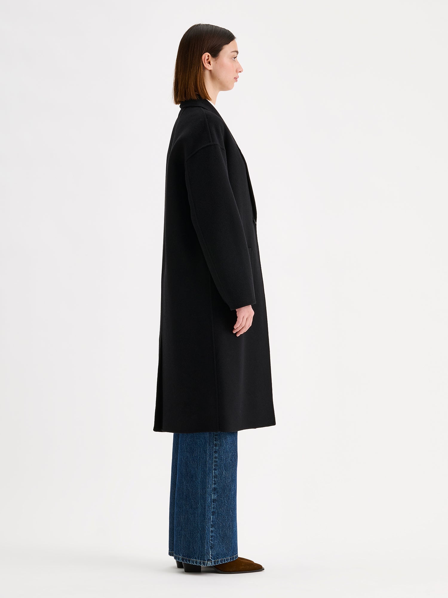 Nanso women's stylish and timeless black YLLE wool coat on a model pictured from the side angle