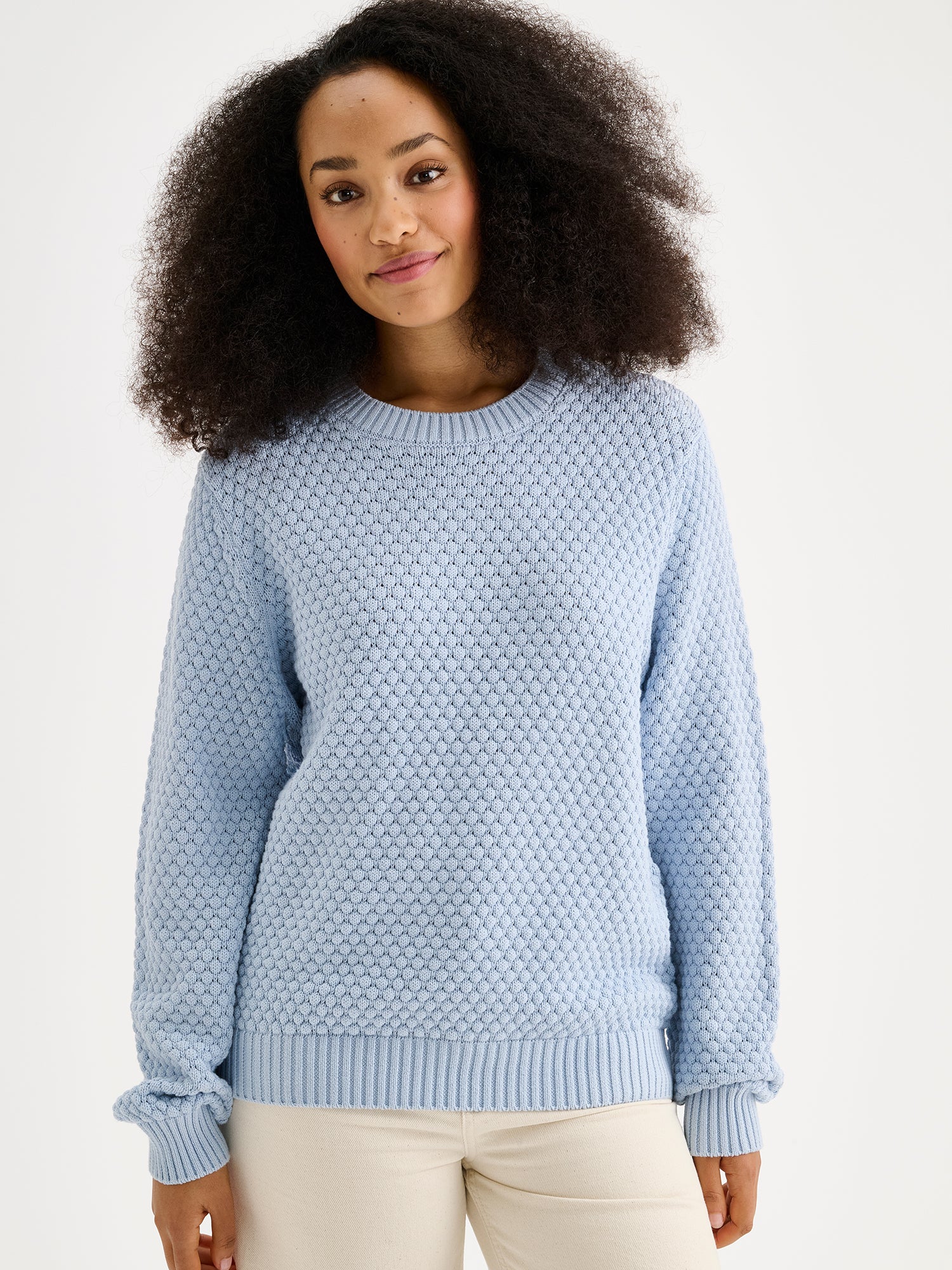Women's KUMPU Knit Sweater in light blue on a model with light jeans, close-up
