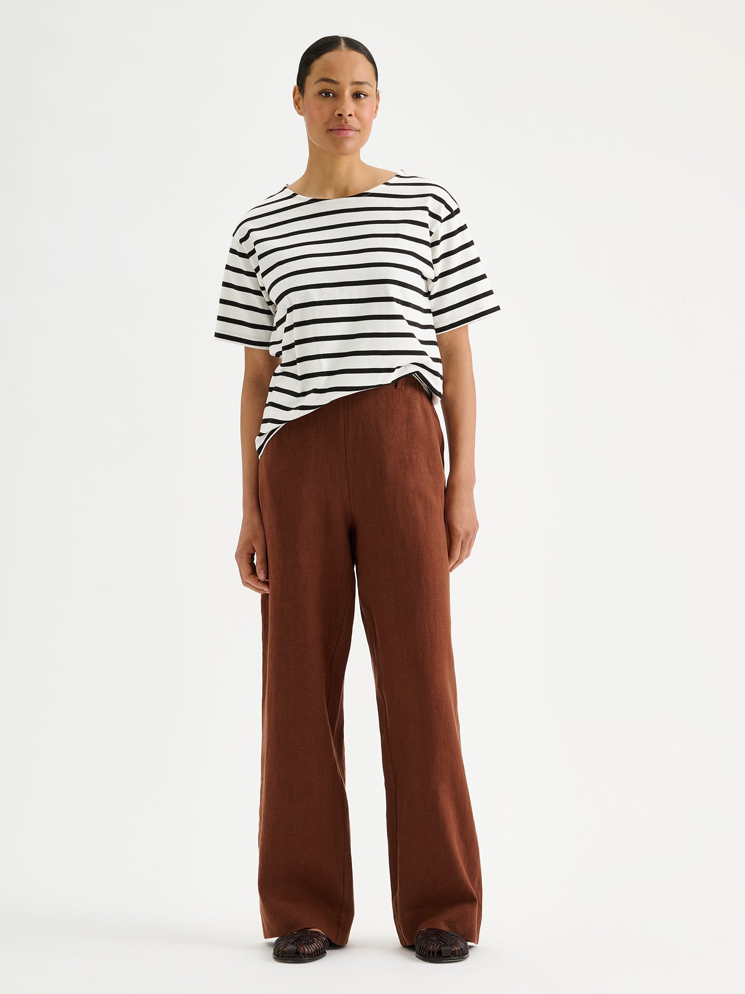 SAARI linen pants in a chic brown color on a model with a striped t-shirt.