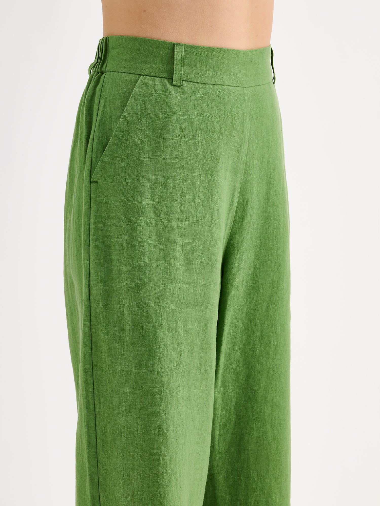 Nanso SAARI linen culottes with elasticated waist and side pockets in a vibrant green shade on a model, close-up.