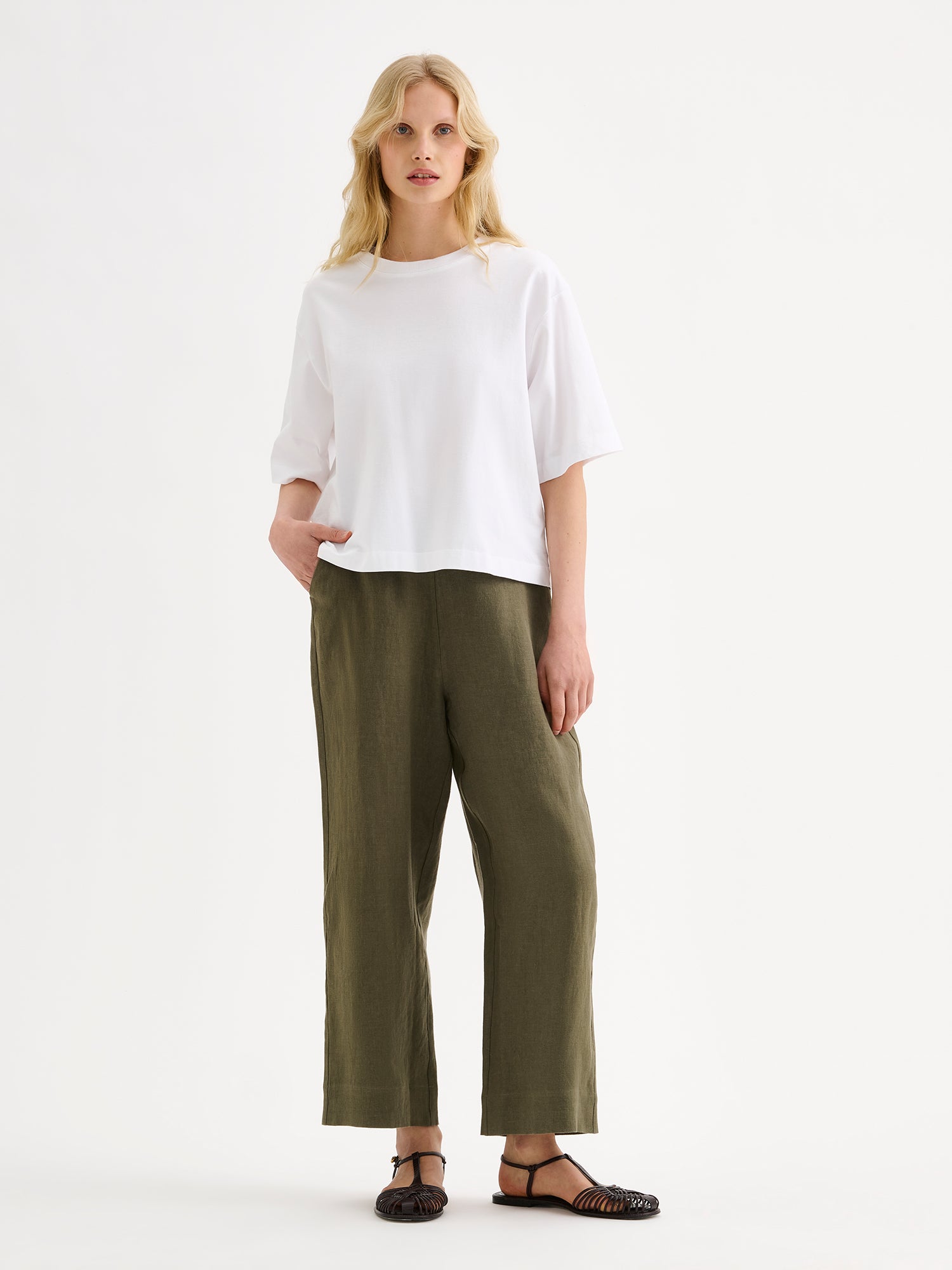 Nanso SAARI linen culottes with elasticated waist and side pockets in a sophisticated olive green shade on a model with a white t-shirt.