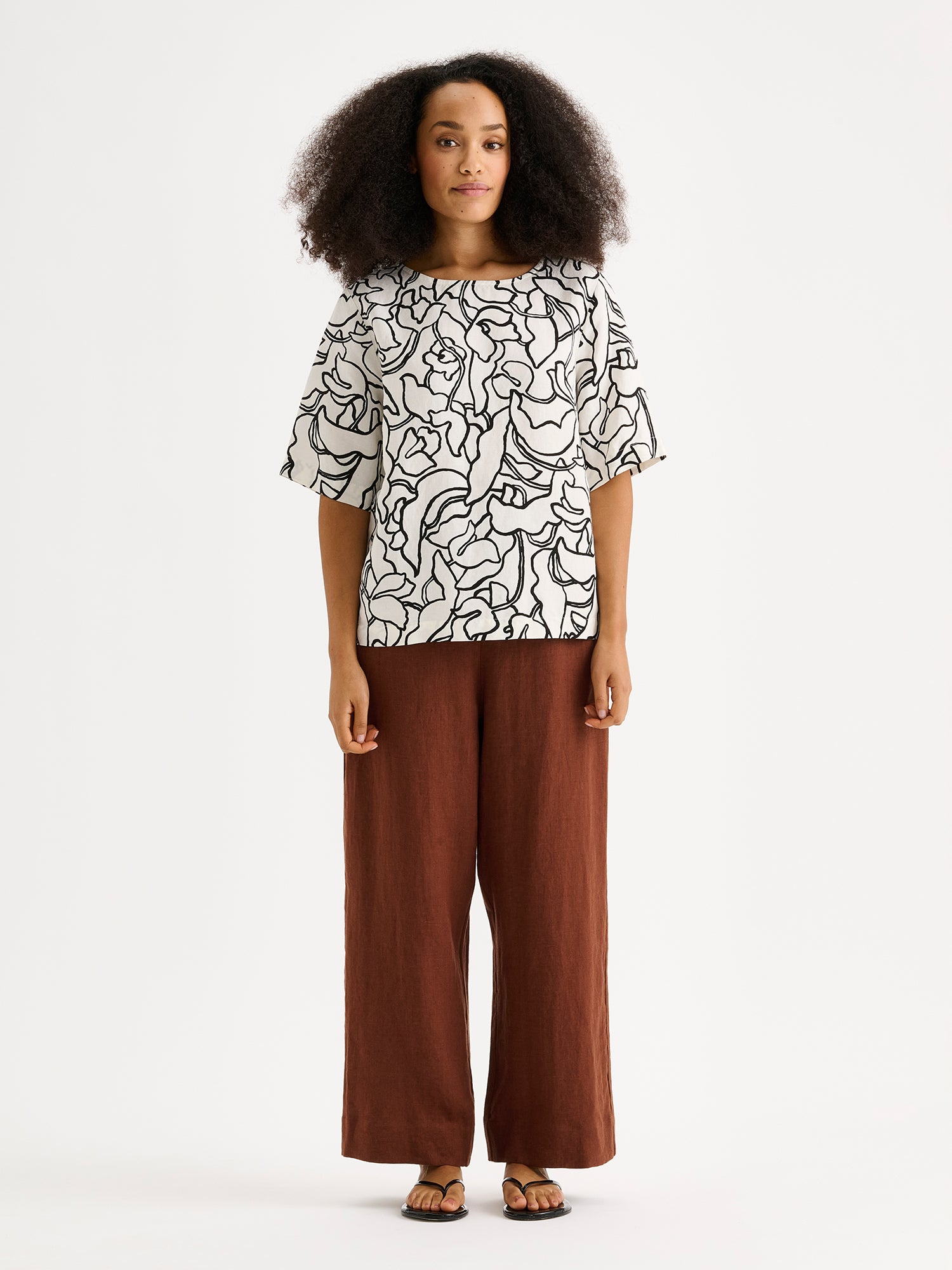 Nanso SAARI linen culottes with elasticated waist and side pockets in a sophisticated brown shade on a model with a patterned black and white blouse.